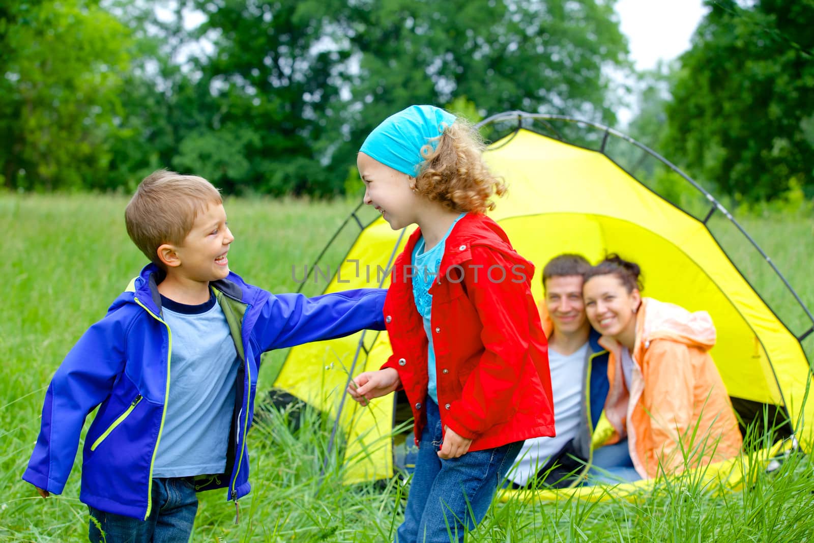 Summer, family camping - lovely sister and brother with parents near camp tent