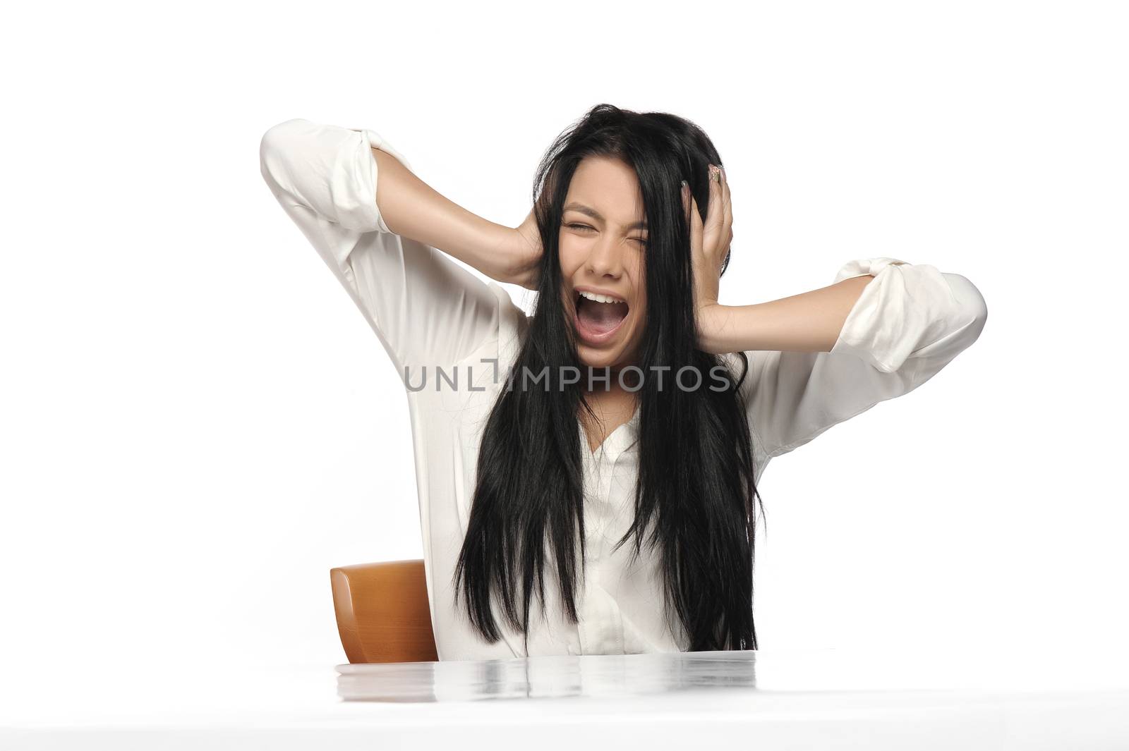 A frustrated and angry woman is screaming out loud and pulling her hair. 