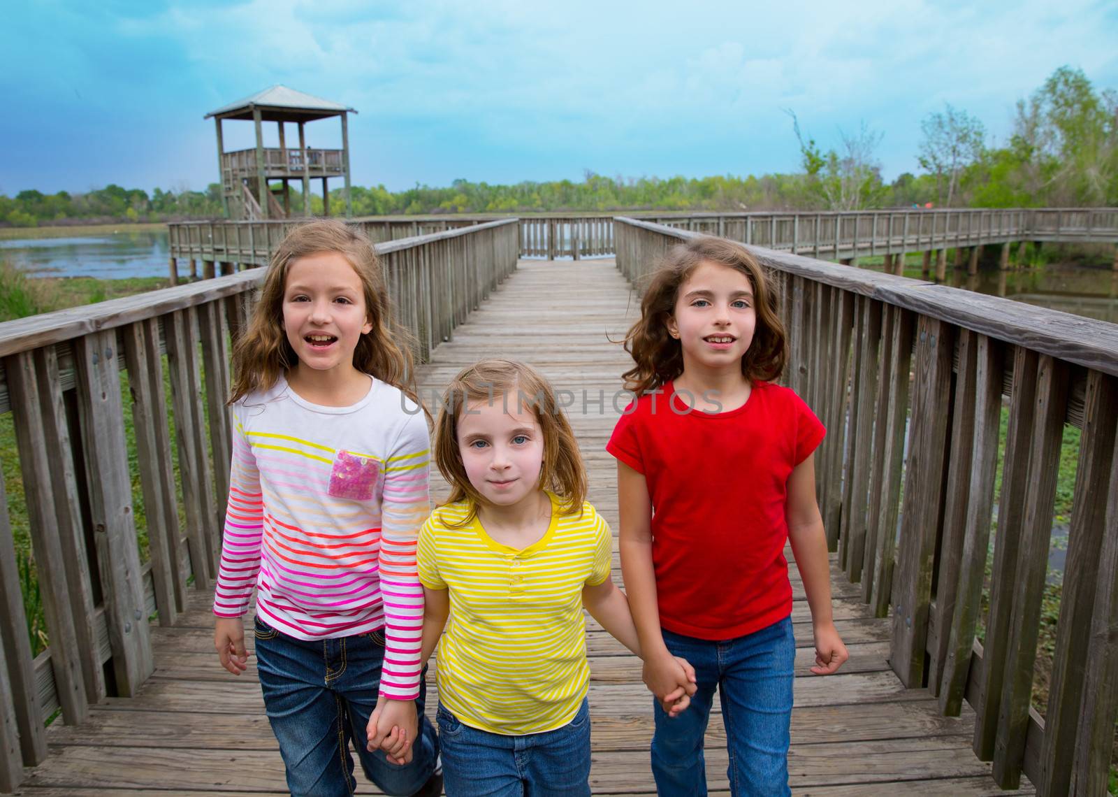 sister friends walking holding hands on lake wood by lunamarina