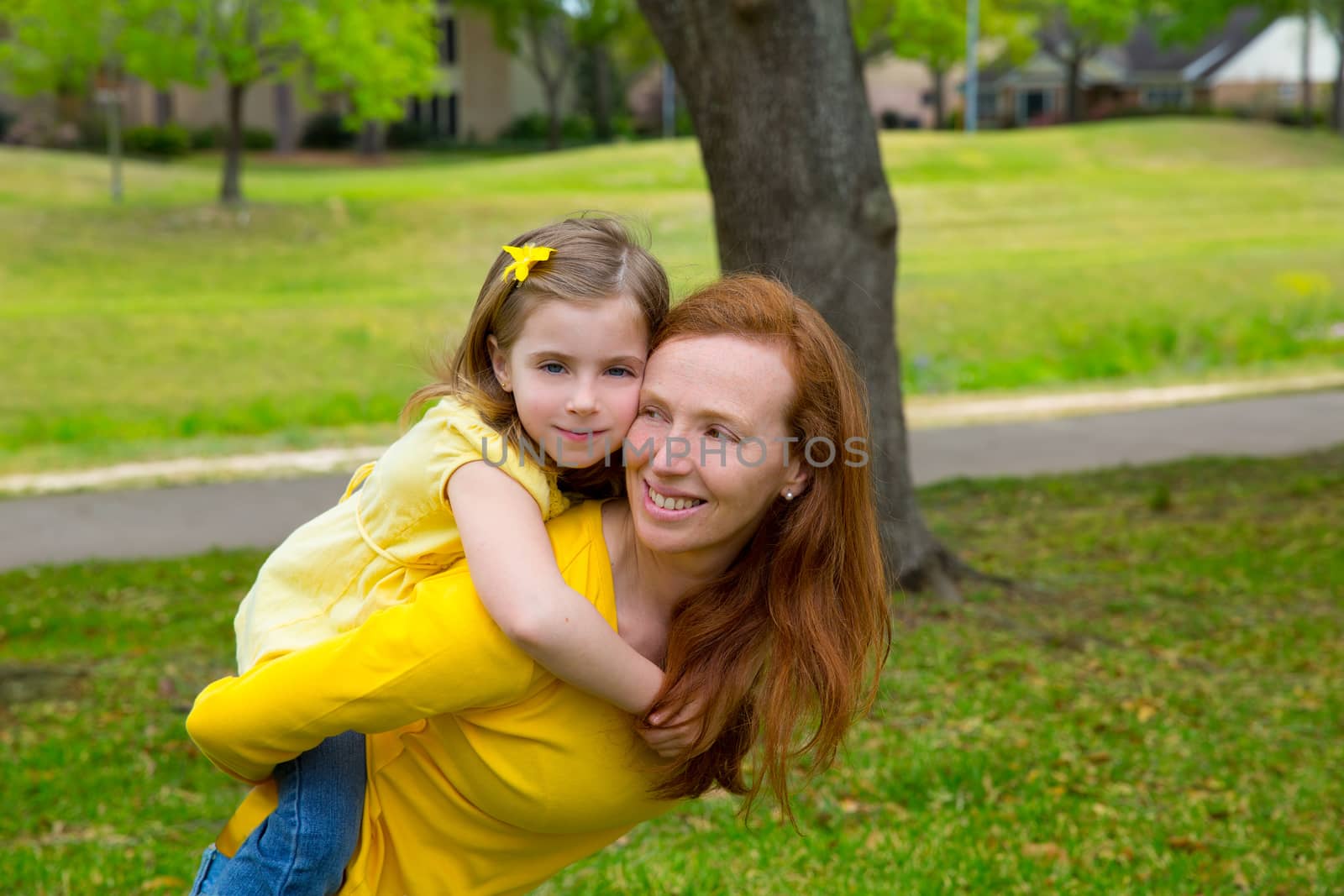 Daughter and mother piggyback smiling in park outdoor by lunamarina