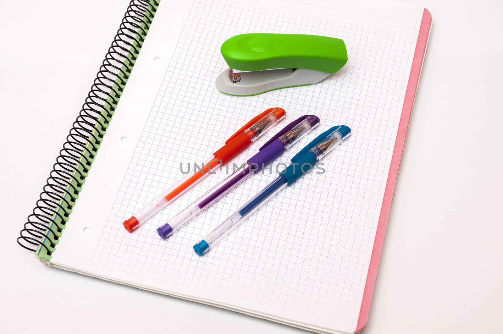 book with pens and stapler on a white background