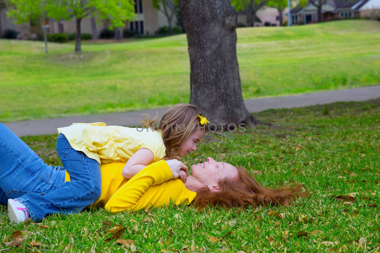 Daughter and mother playing lying on park lawn by lunamarina