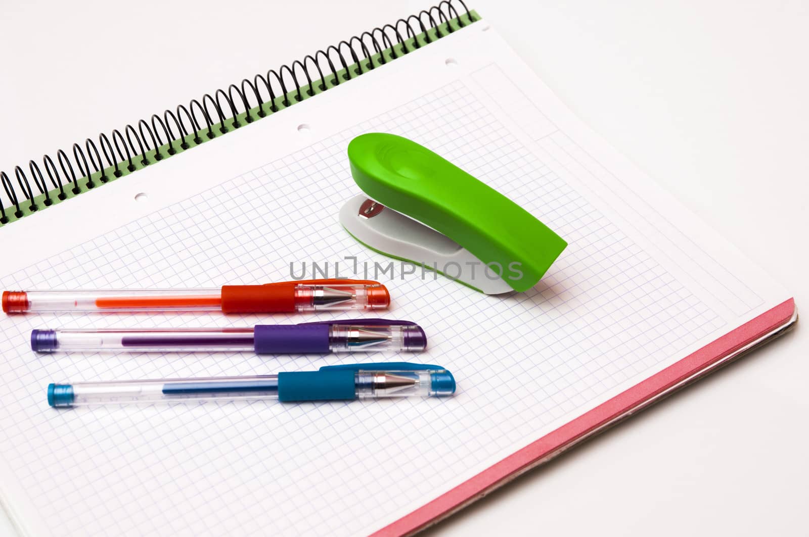 book with pens and stapler on a white background