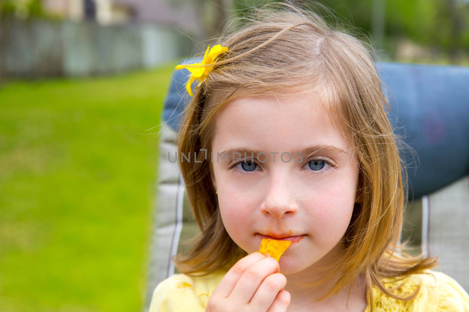 Blond kid girl eating corn snacks in outdoor park by lunamarina