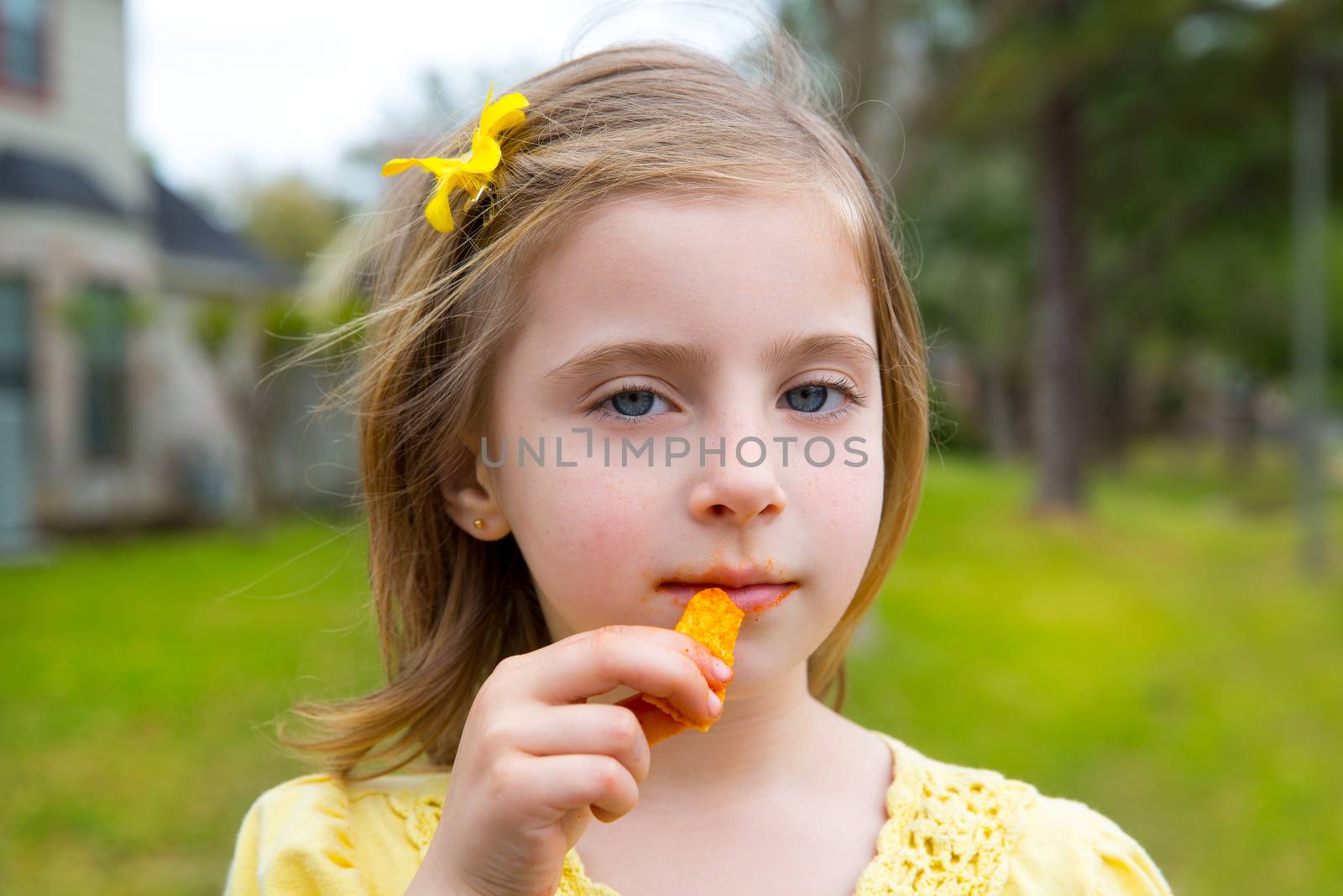 Blond kid girl eating corn snacks in outdoor park by lunamarina