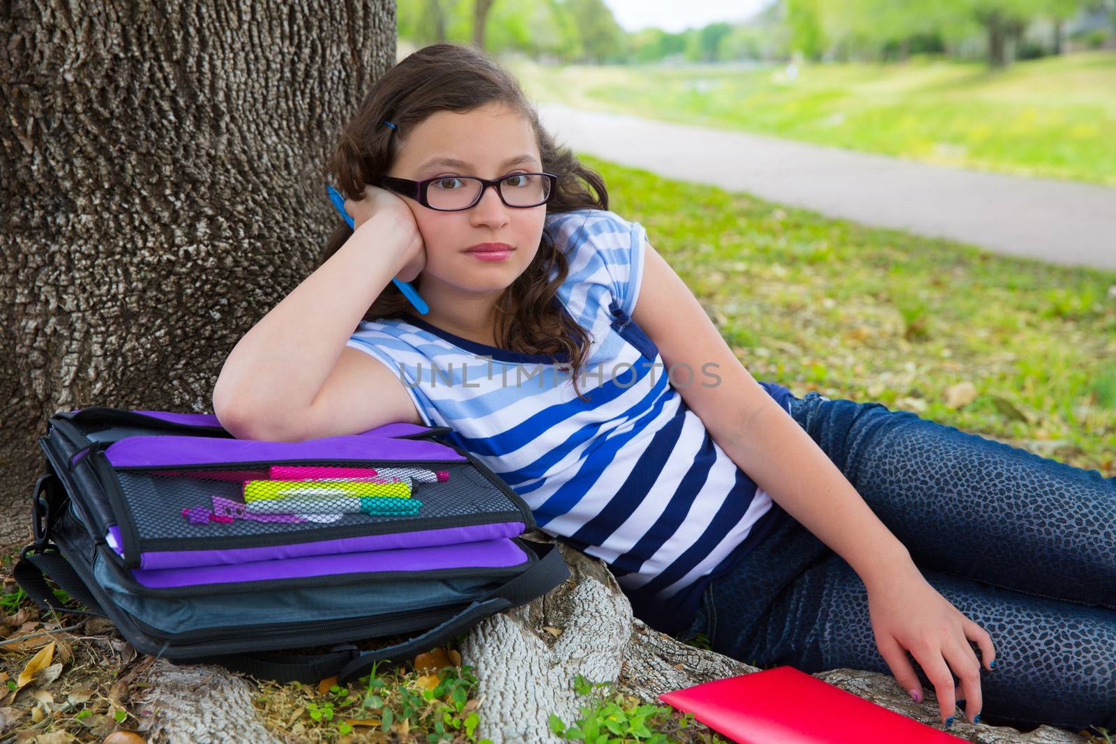 Clever student teen girl with school bag under park tree by lunamarina