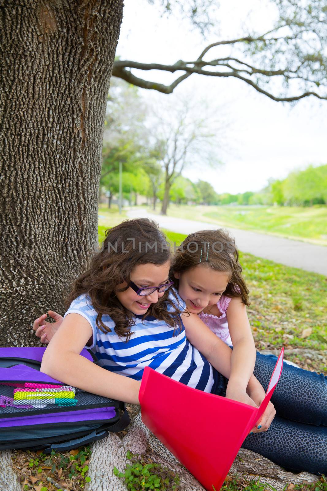 sister firends girls relaxed under tree park after school with bag and folders