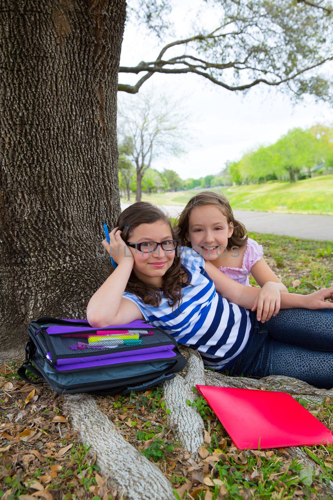 sister firends girls relaxed under tree park after school by lunamarina