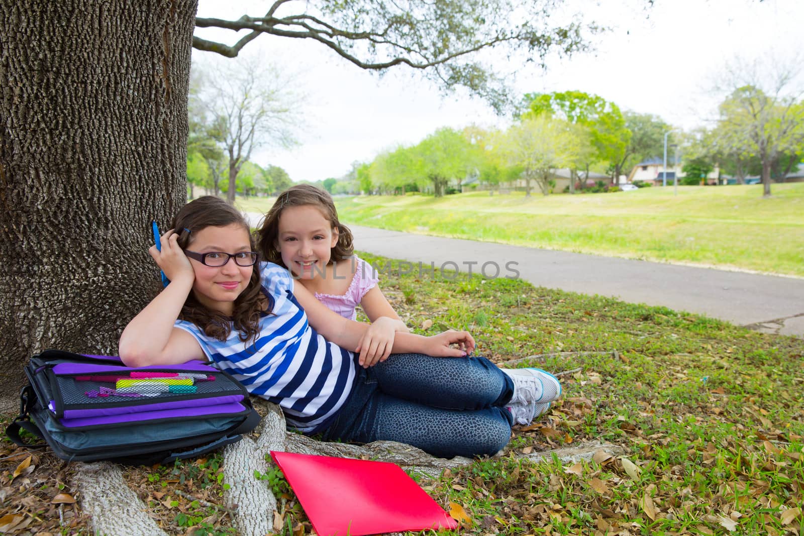 sister firends girls relaxed under tree park after school with bag and folders
