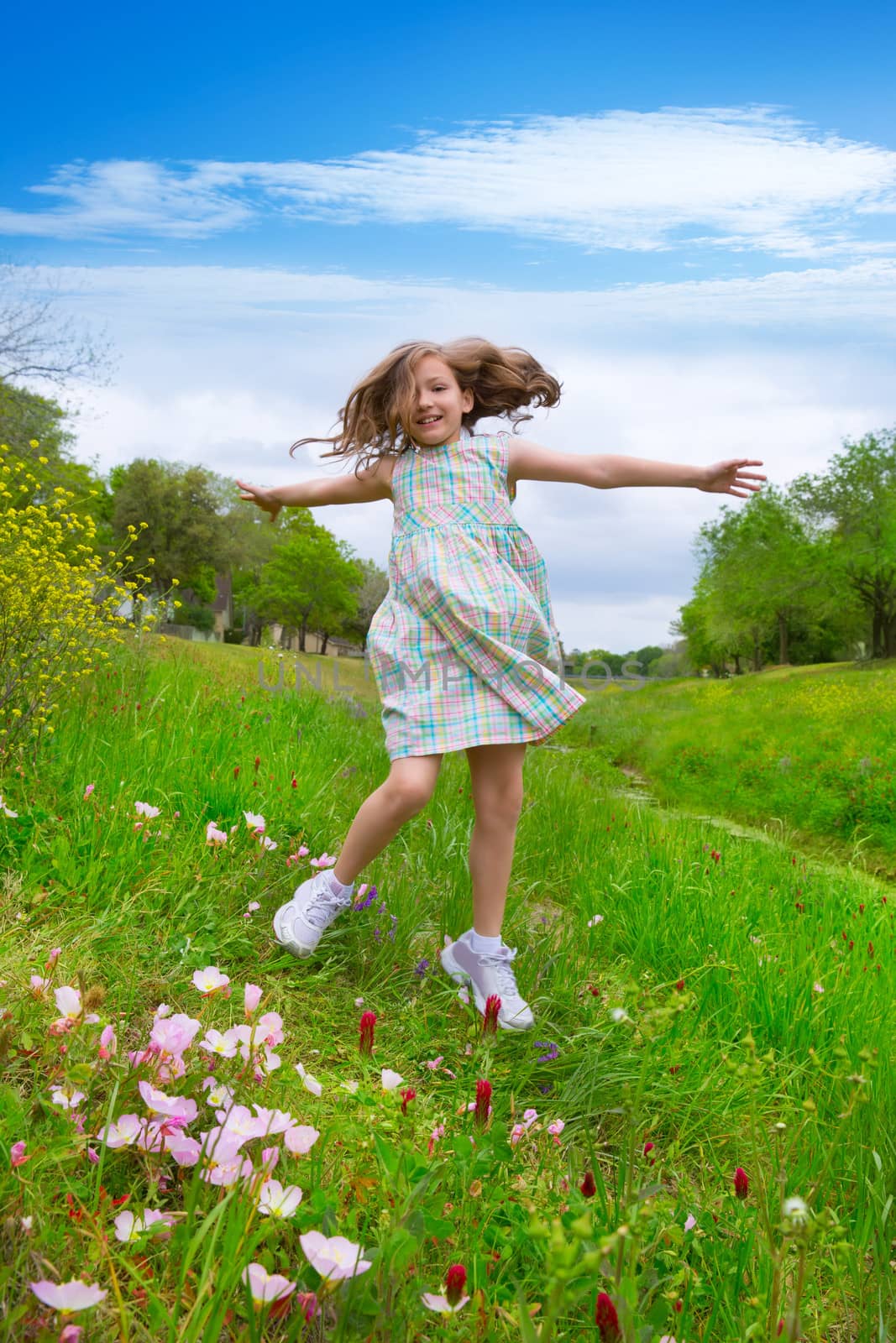 happy children girl jumping on spring poppy flowers by lunamarina