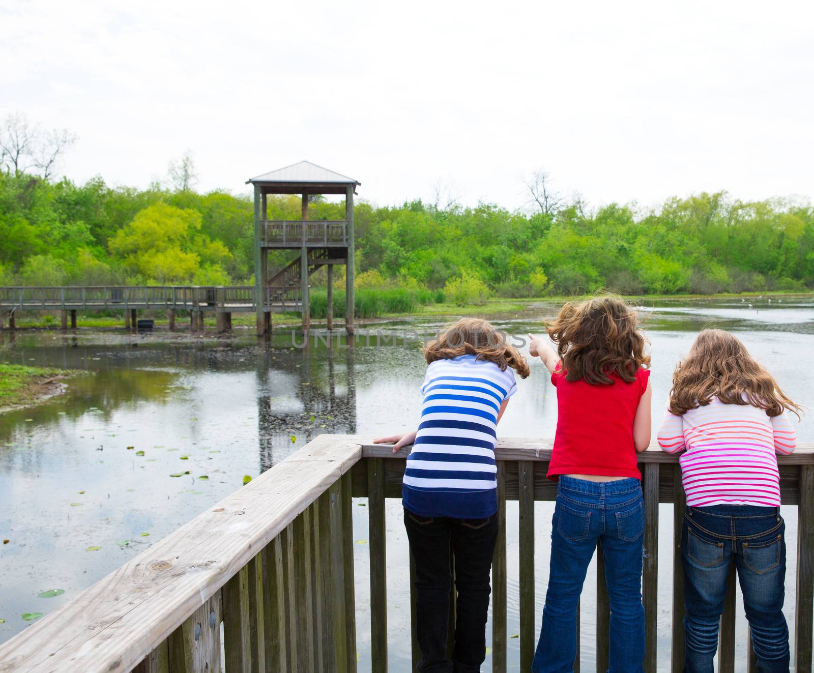 kid children girls looking and pointing at park lake in Texas rear view