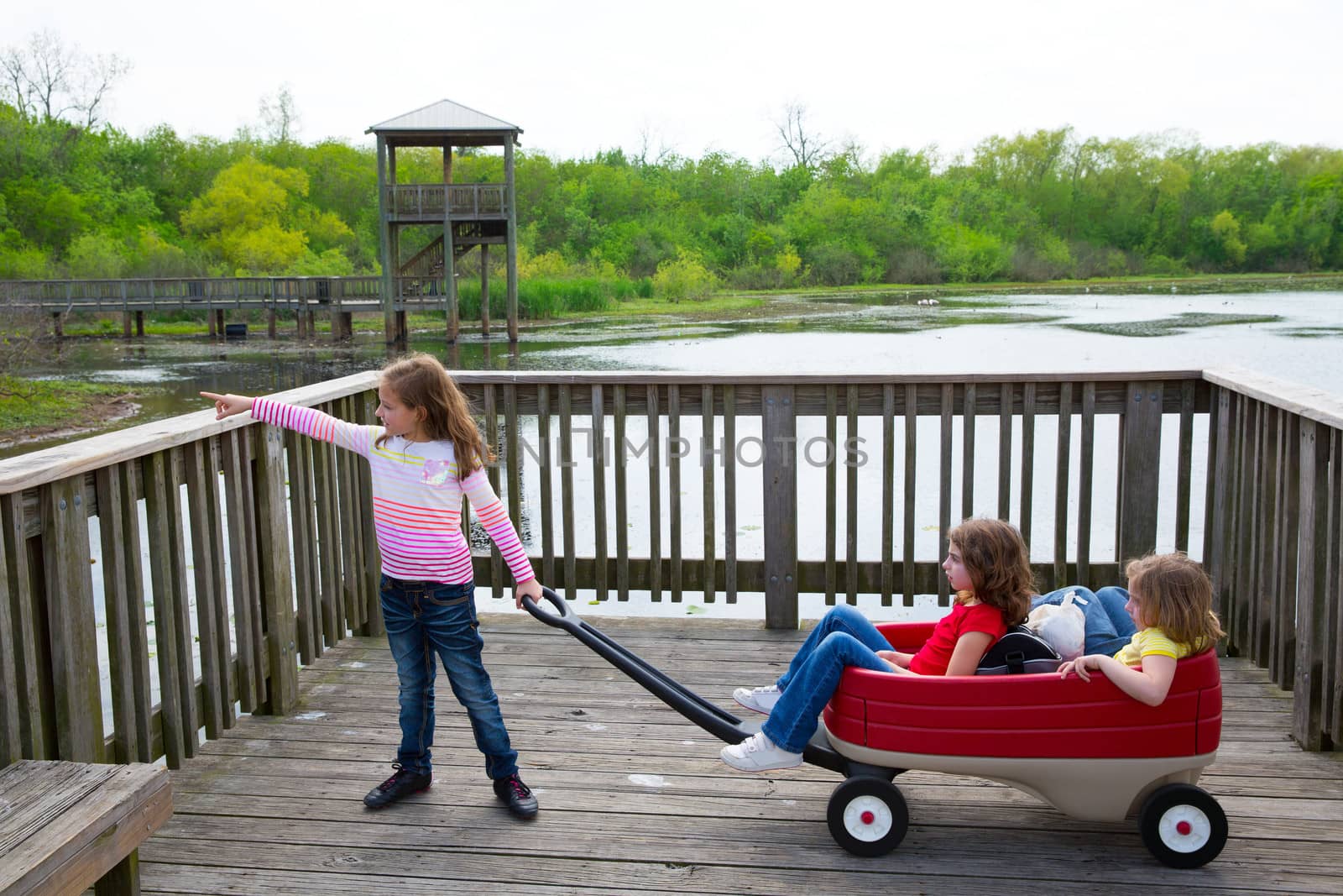 girls looking at park lake with outdoor dump cart by lunamarina