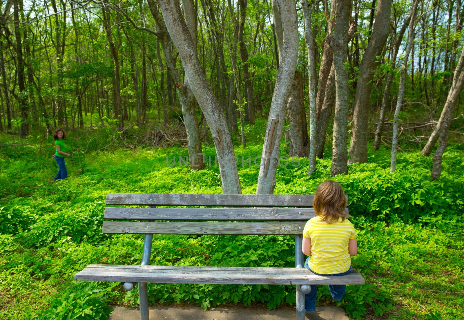 Lonely children sad looking the forest girl sitting at the park bench