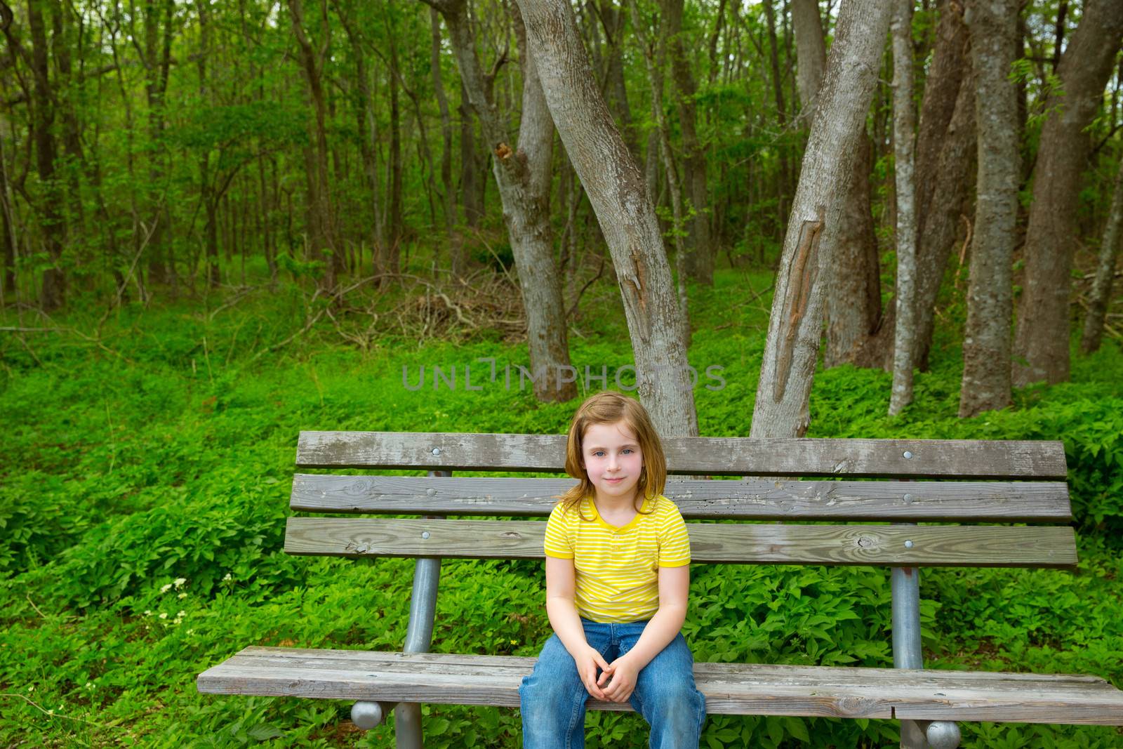 Lonely children girl happy sitting on park bench by lunamarina