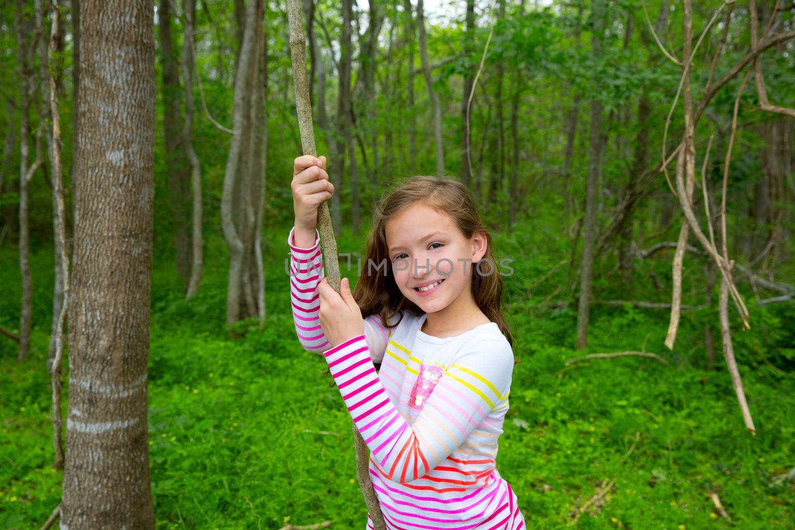 Happy children girl playing in forest park jungle with liana smiling
