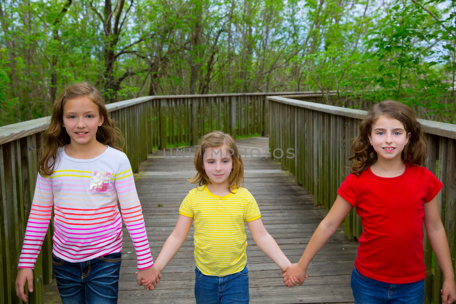 sister friends walking holding hands on lake wood smiling