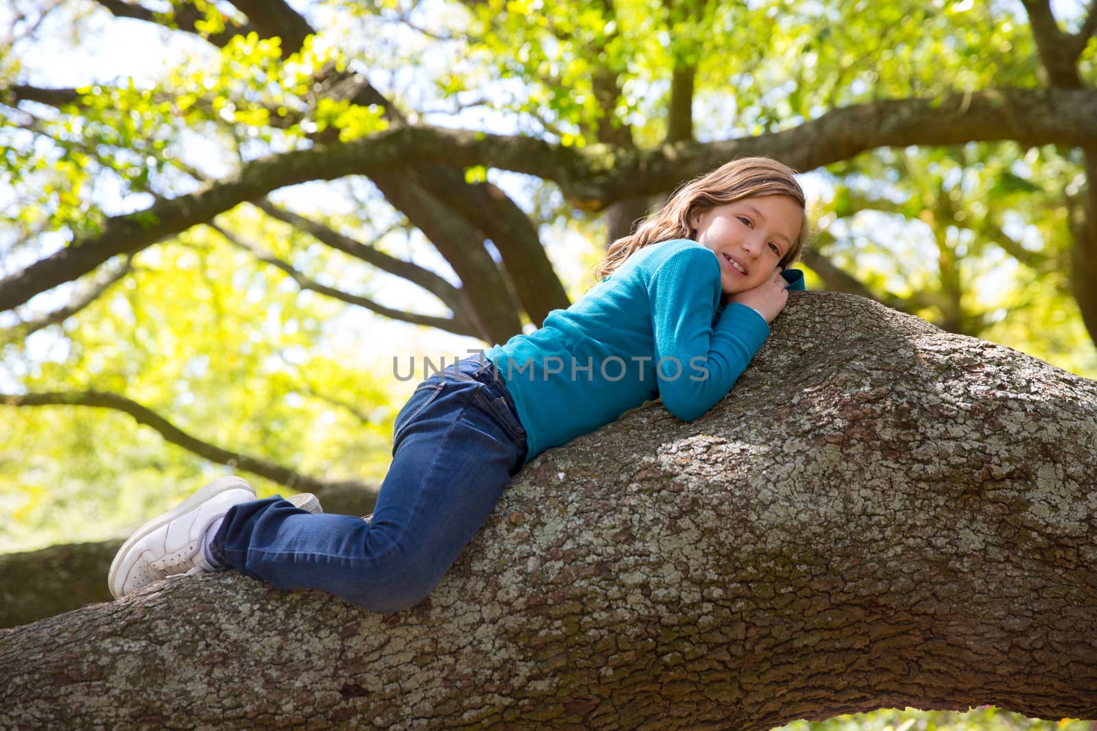 Beautiful children kid girl resting lying on a tree branch