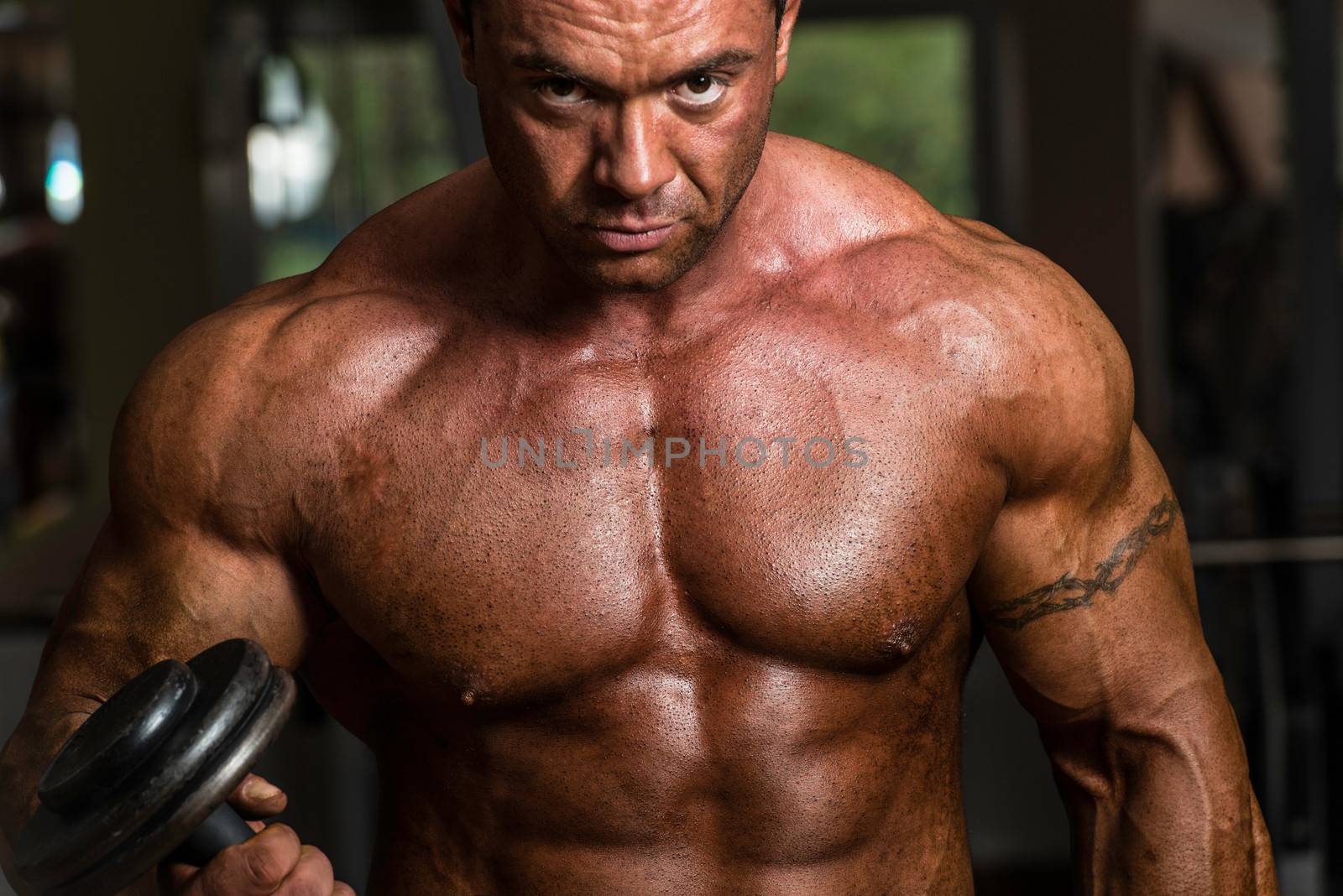 bodybuilder doing heavy weight exercise for biceps with dumbbell by JalePhoto