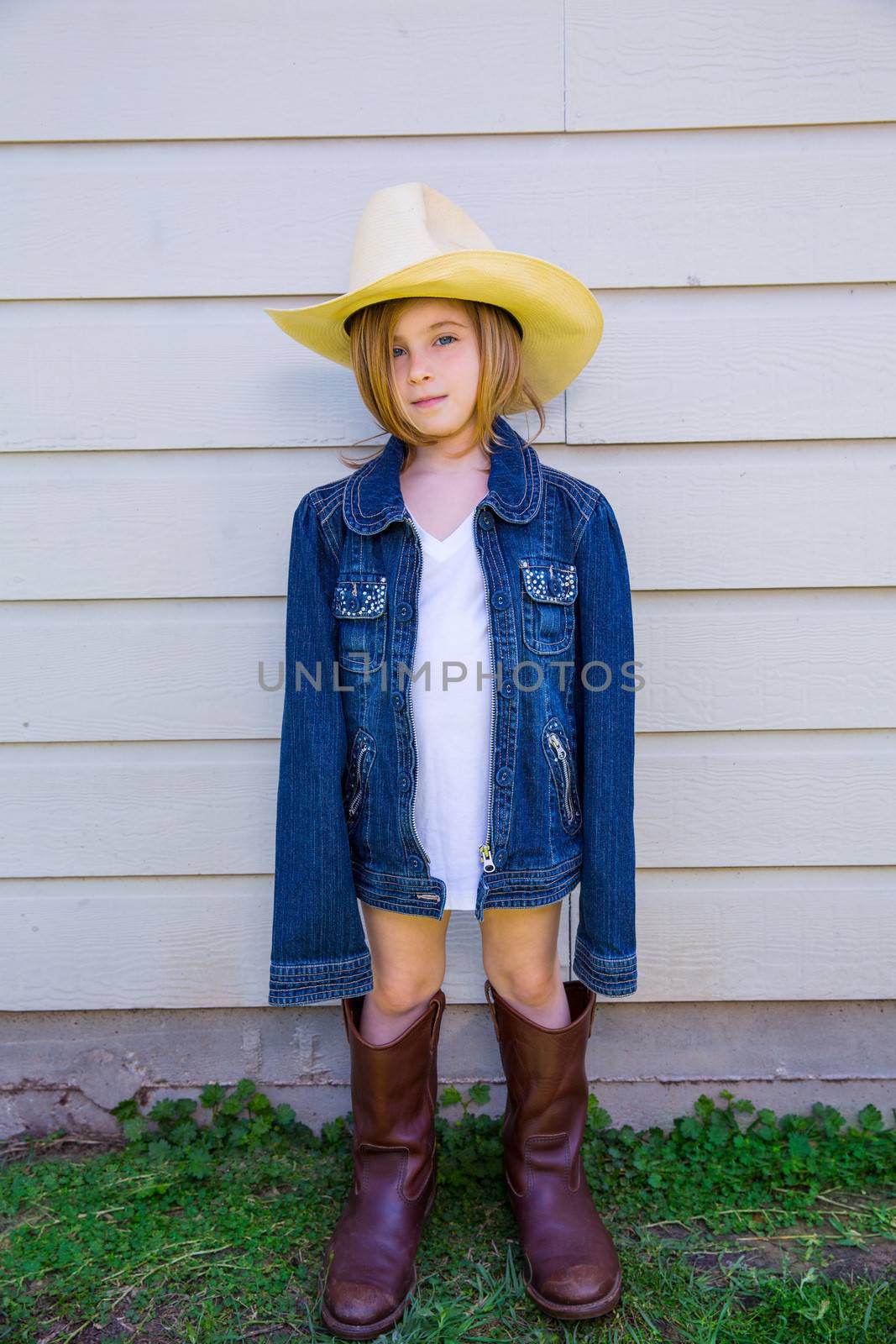 Little kid girl pretending to be a cowboy with father boots and hat