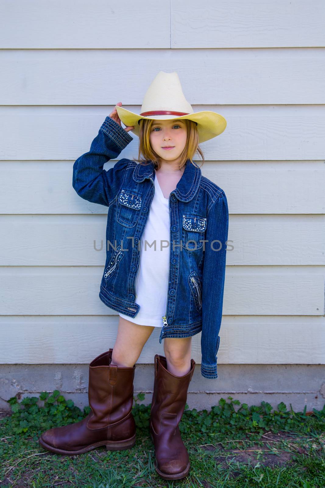 Little kid girl pretending to be a cowboy with father boots and hat