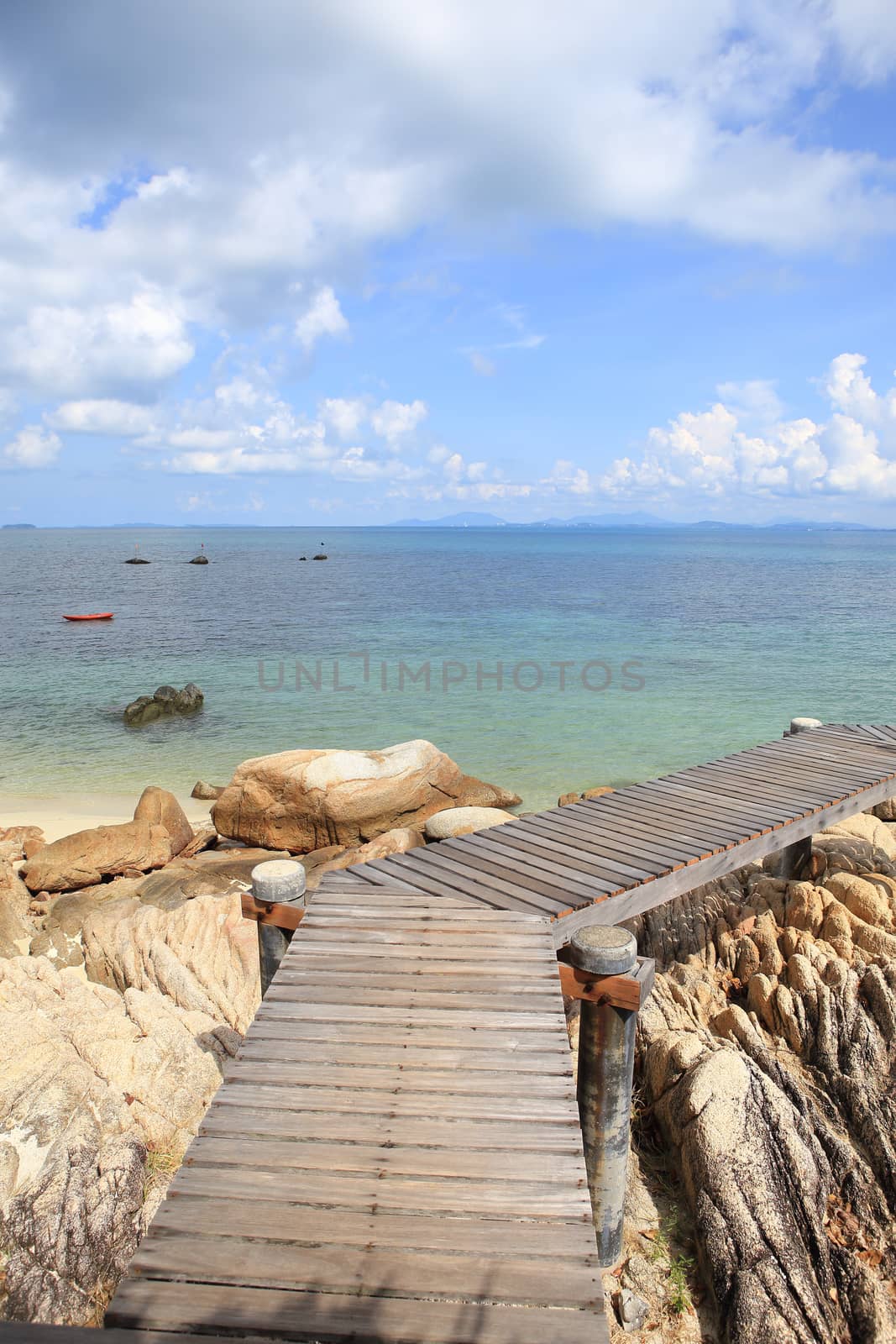 Wooden jetty on tropical beach on island by rufous