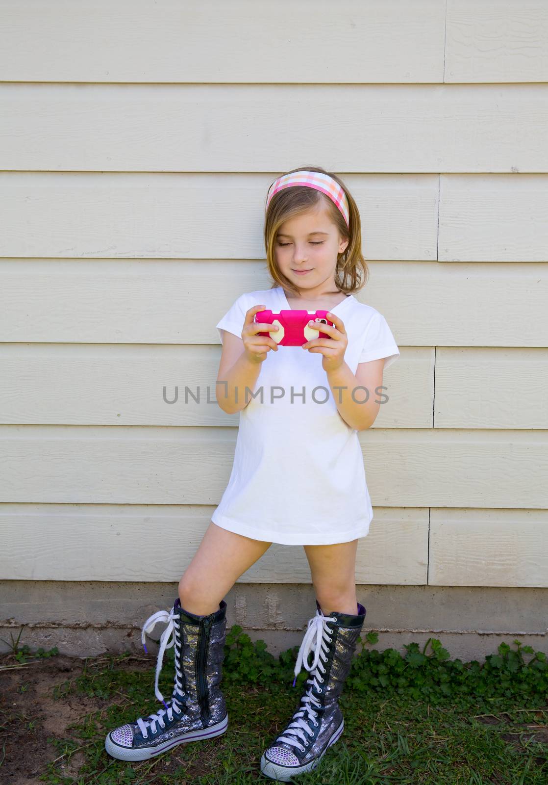 blond little fashion kid girl playing with smartphone by lunamarina