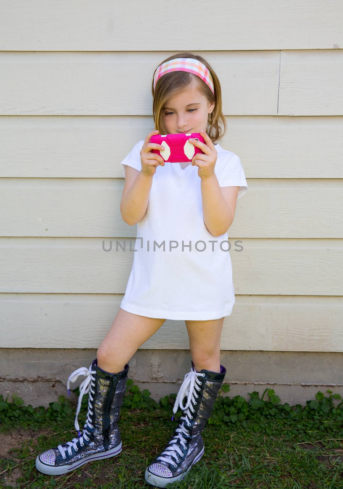 blond little fashion kid girl playing with pink smartphone