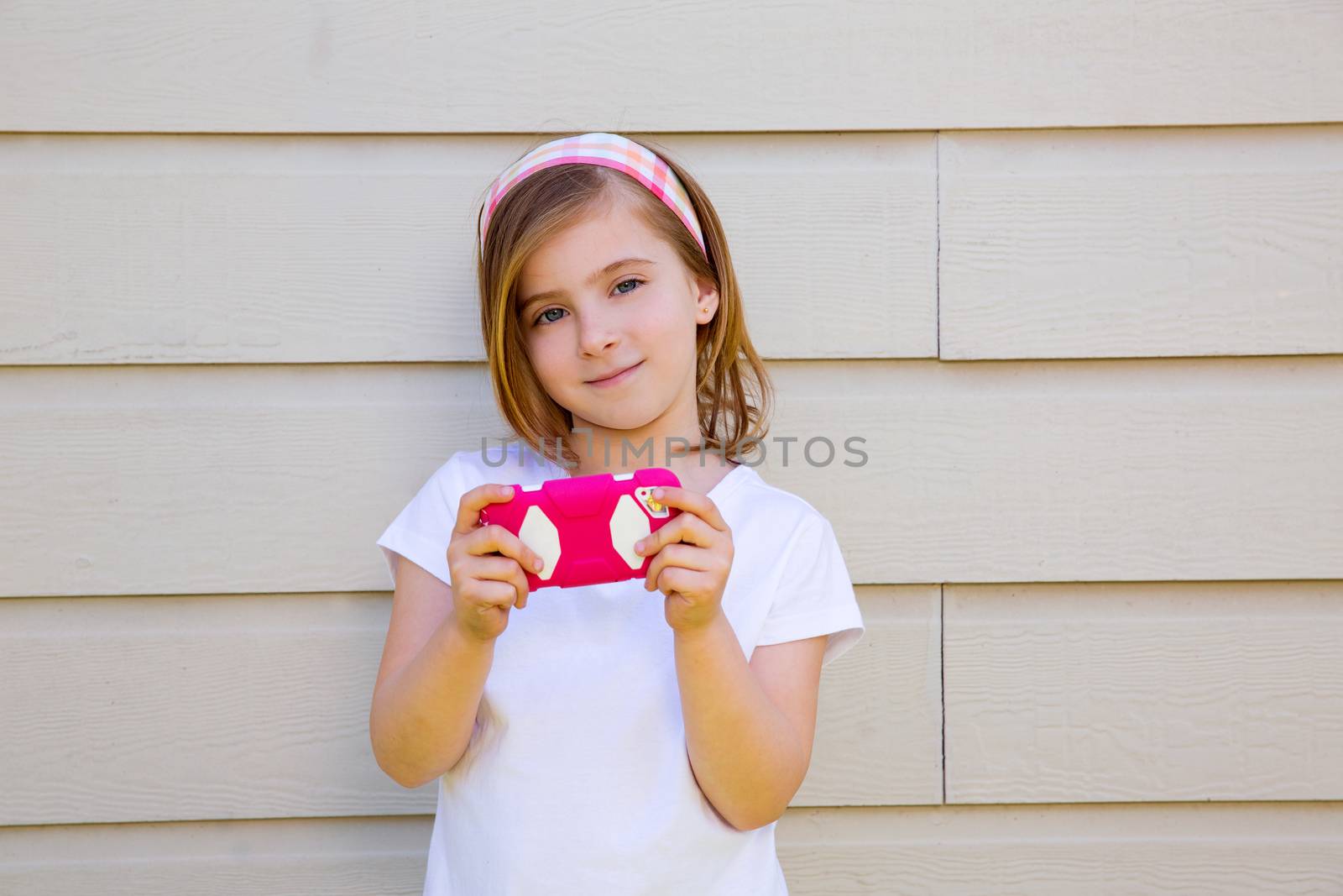blond little fashion kid girl playing with pink smartphone