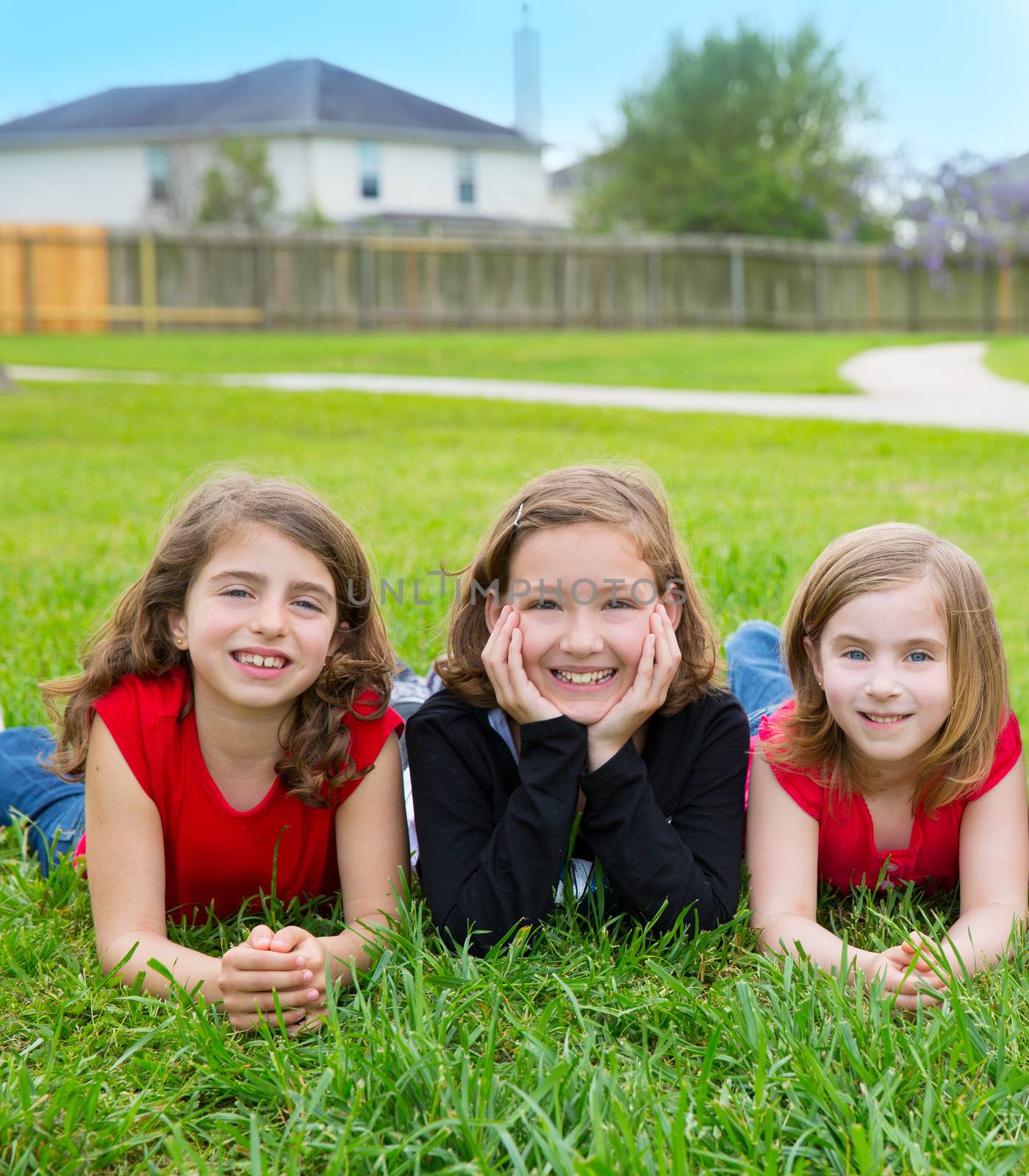 Children girls group lying on lawn grass smiling happy by lunamarina