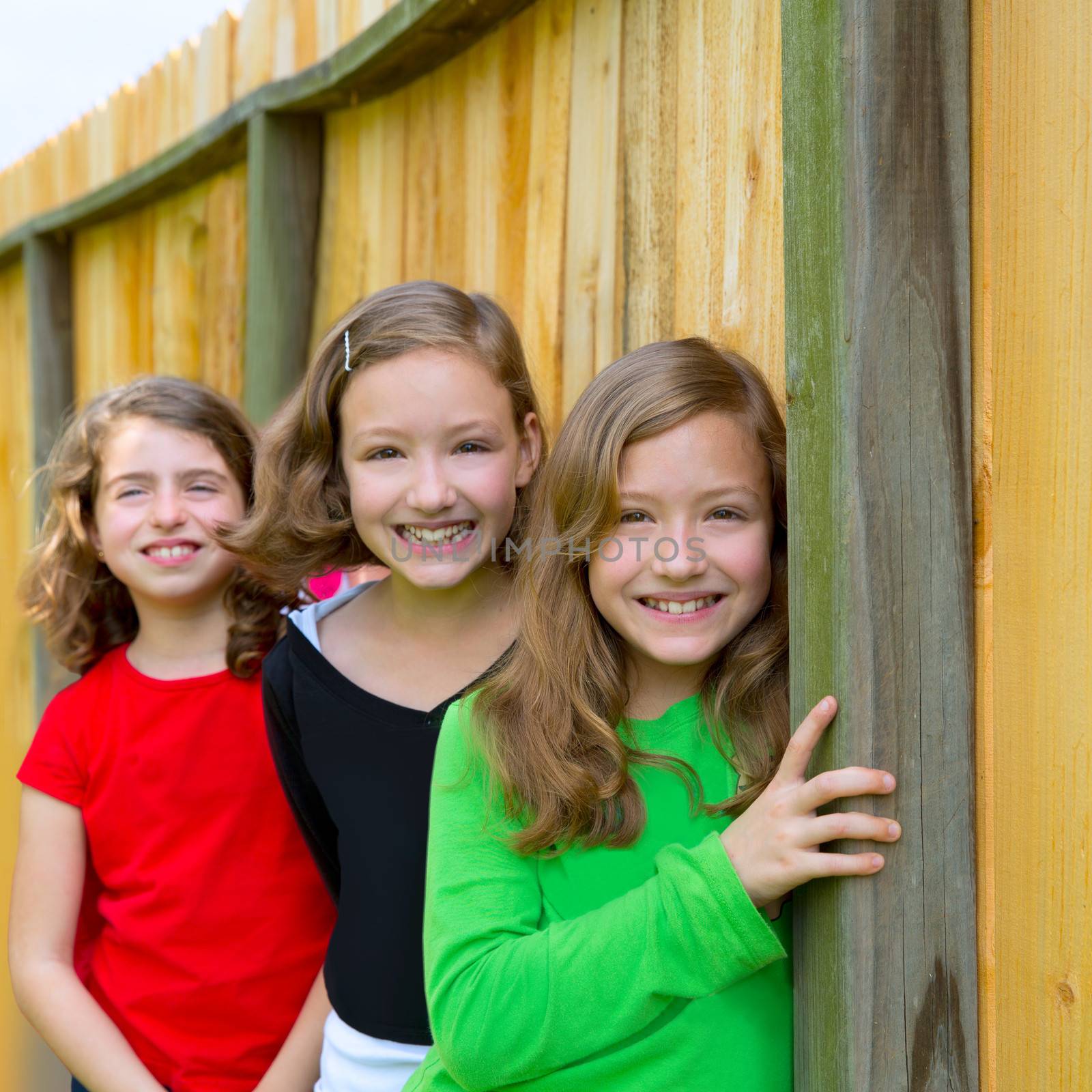 Grils group in a row smiling in a wooden fence by lunamarina