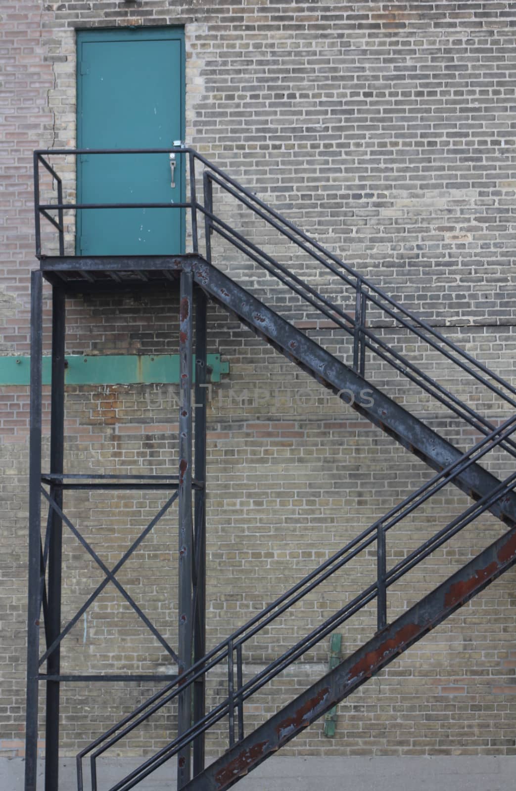 A blue door and fire escape against a brick wall in an industrial building.