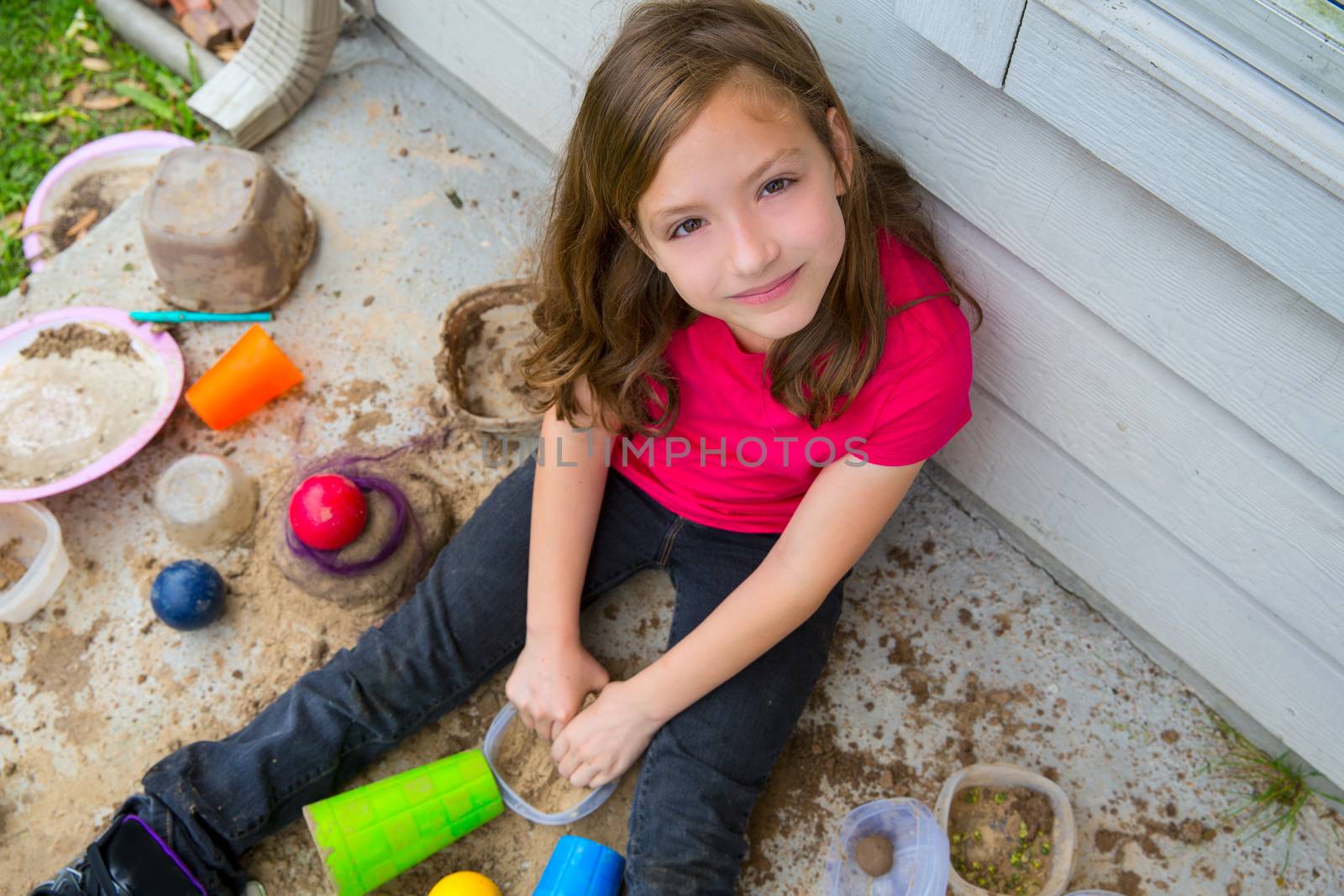 girl playing with mud in a messy soil smiling portrait by lunamarina