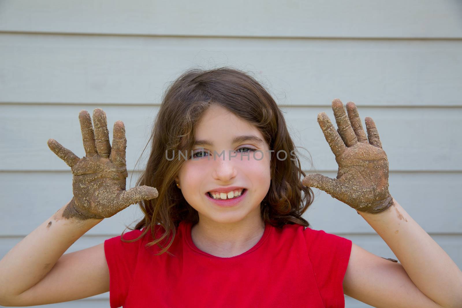 happy kid girl playing with mud with dirty hands smiling by lunamarina