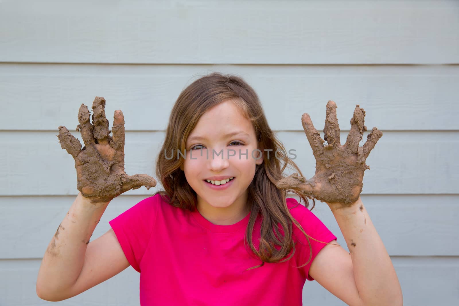 happy kid girl playing with mud with dirty hands smiling by lunamarina