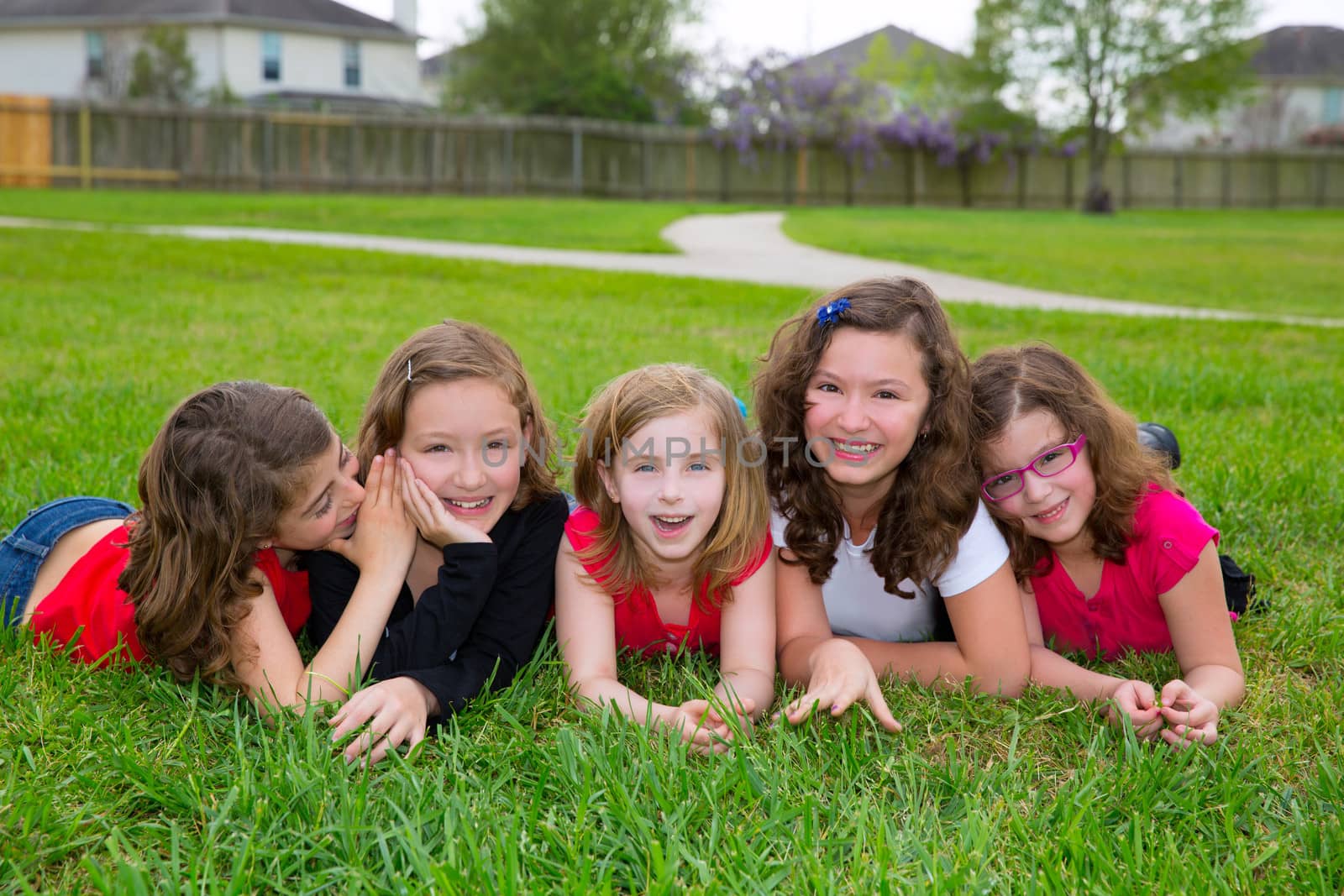 Children girls group lying on lawn grass smiling happy together in a row