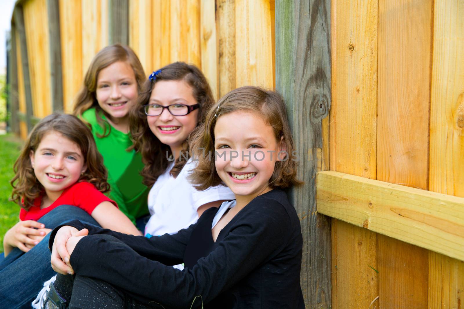 Grils group in a row smiling in a wooden fence outdoor