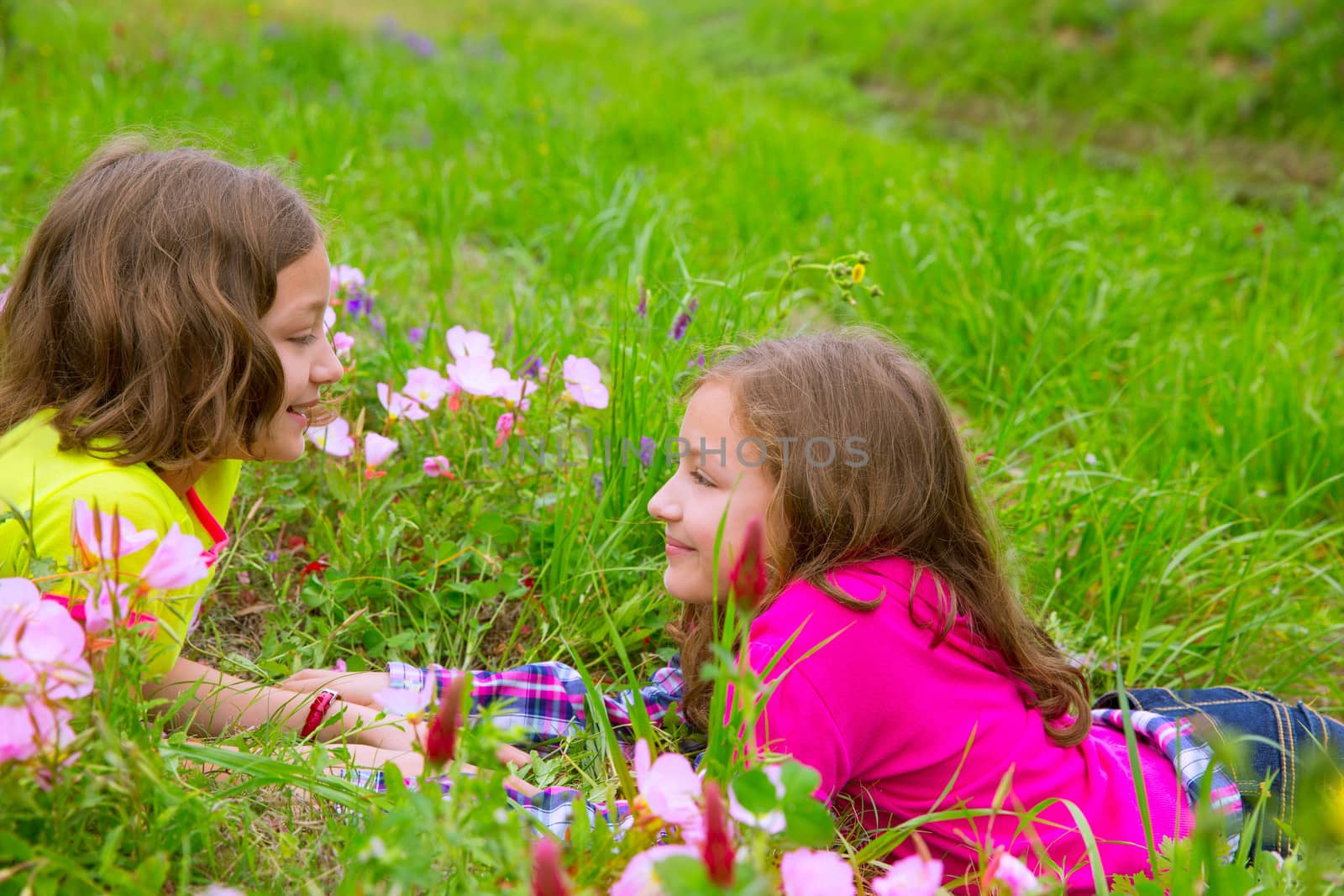 happy twin sister girls playing on spring flowers meadow by lunamarina