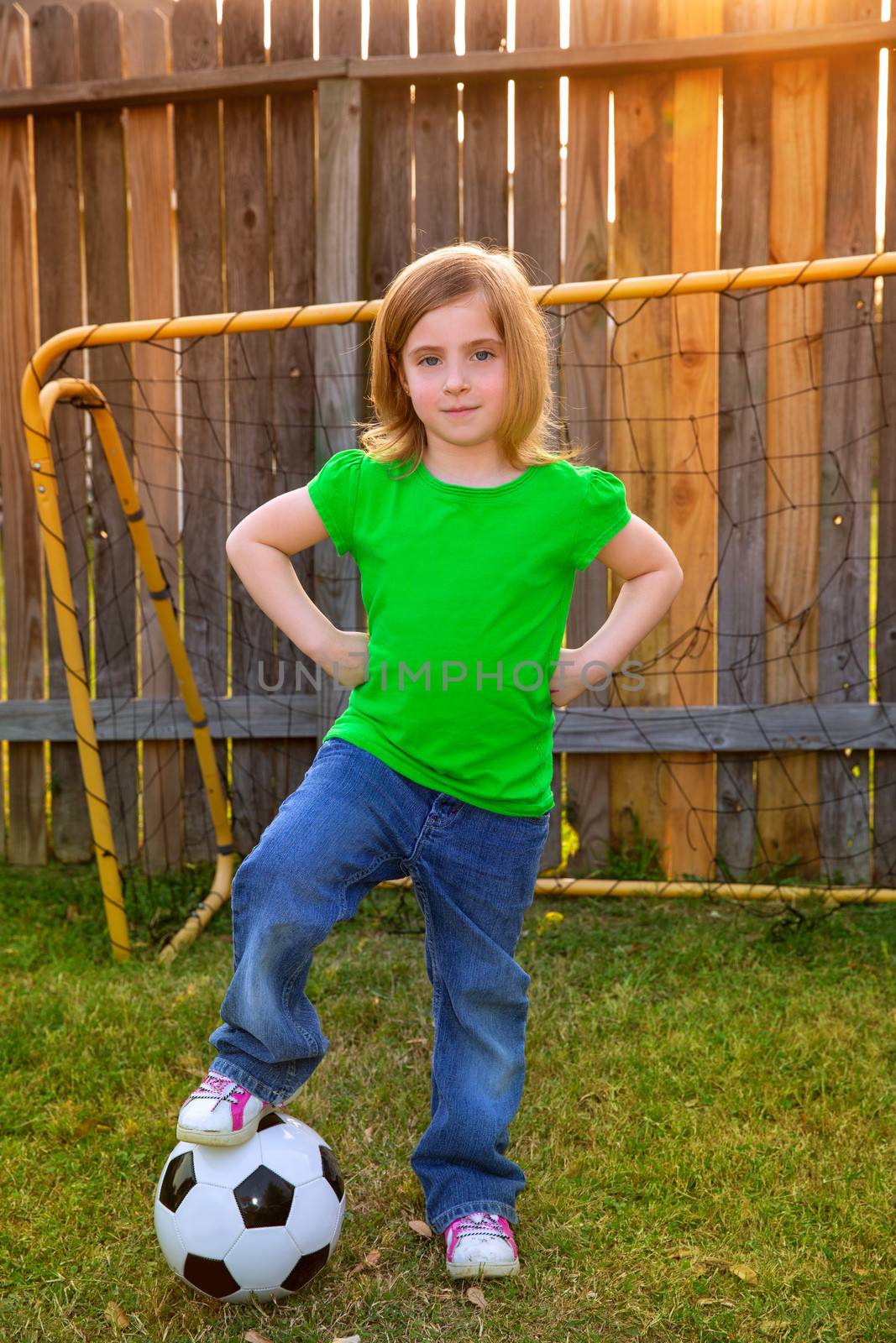 Blond little girl soccer player happy in backyard with ball