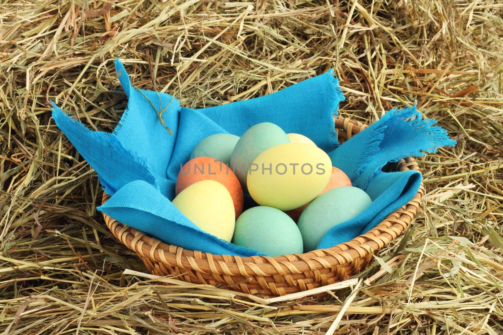 Basket of colored easter eggs in basket on hay