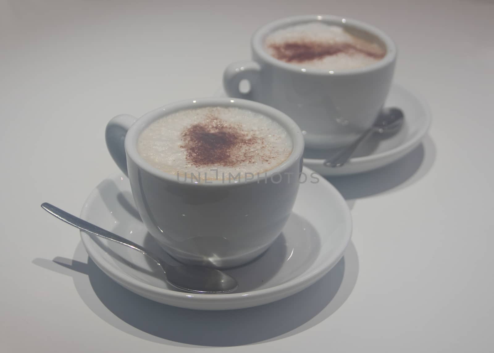Two cups of capuccino soft focus on white
