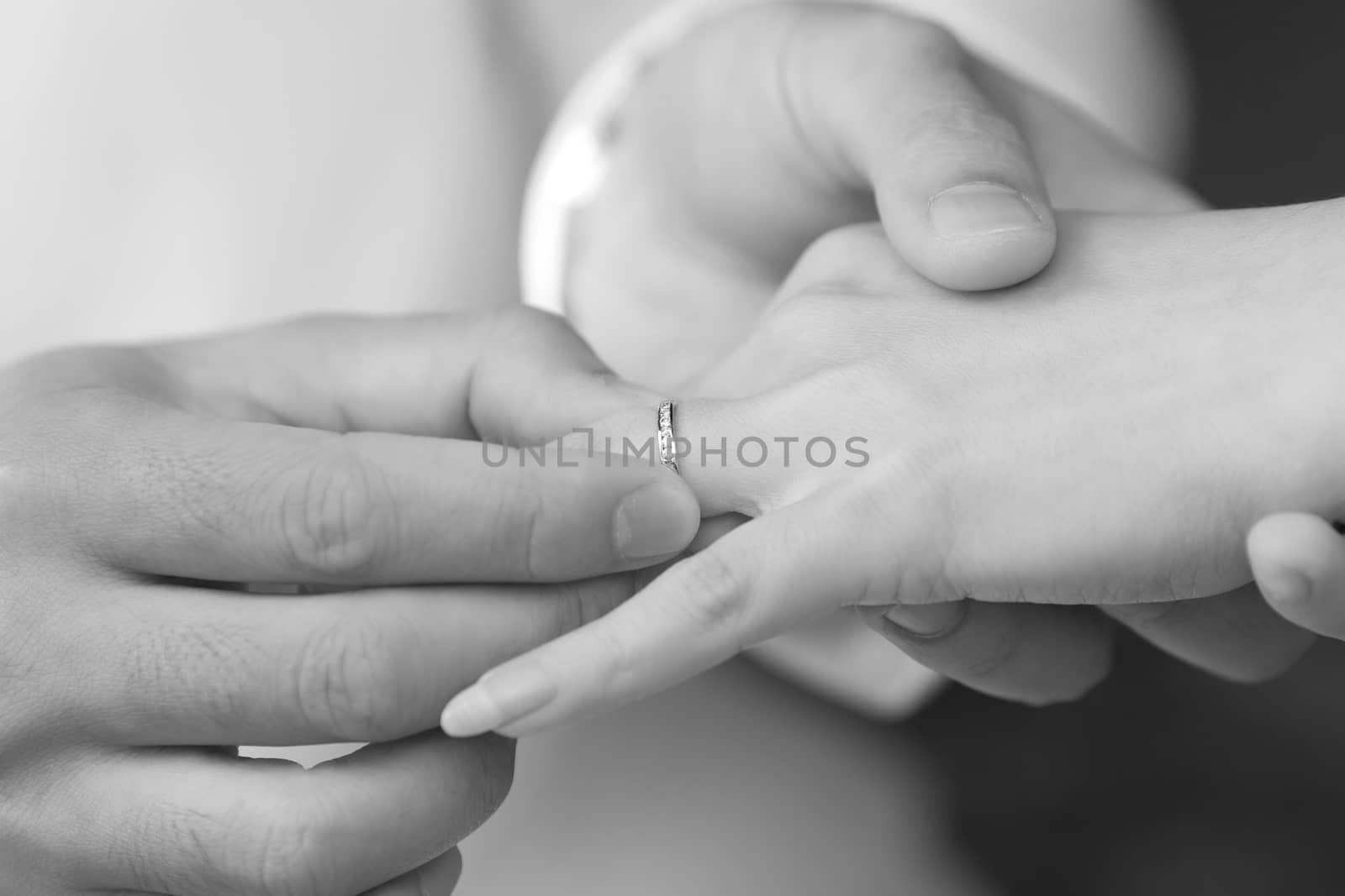 groom put an engagement ring on bride finger by tanatat