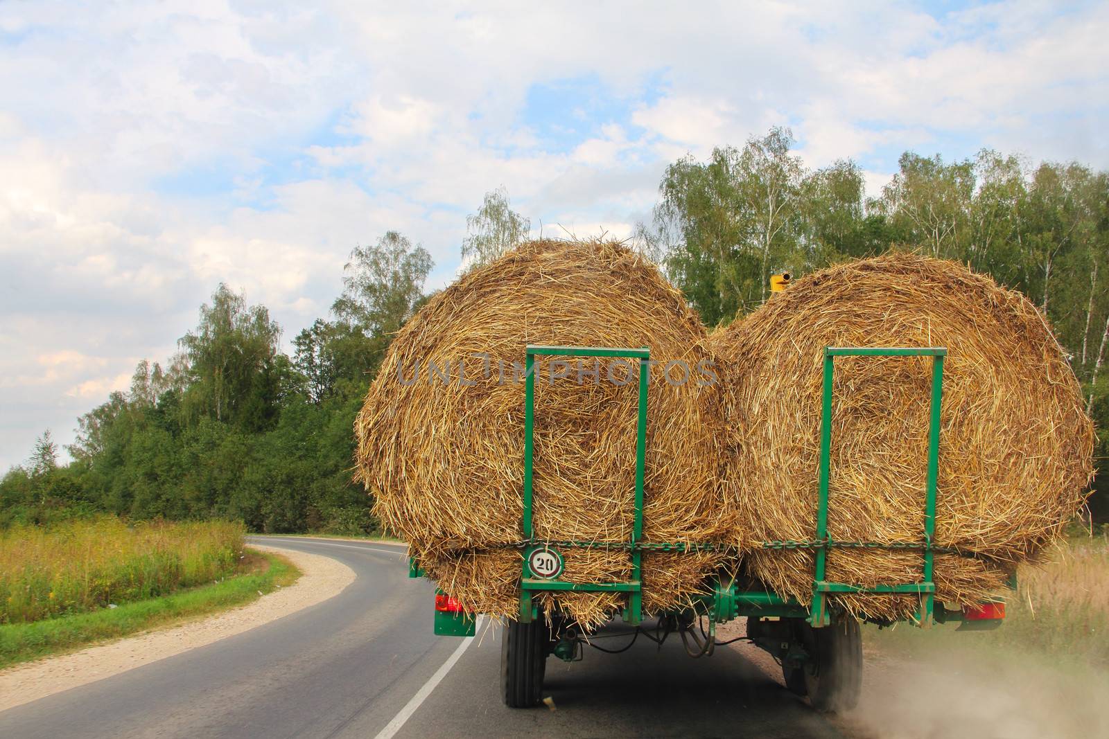 Transportation of haystacks after harvesting at sunny day