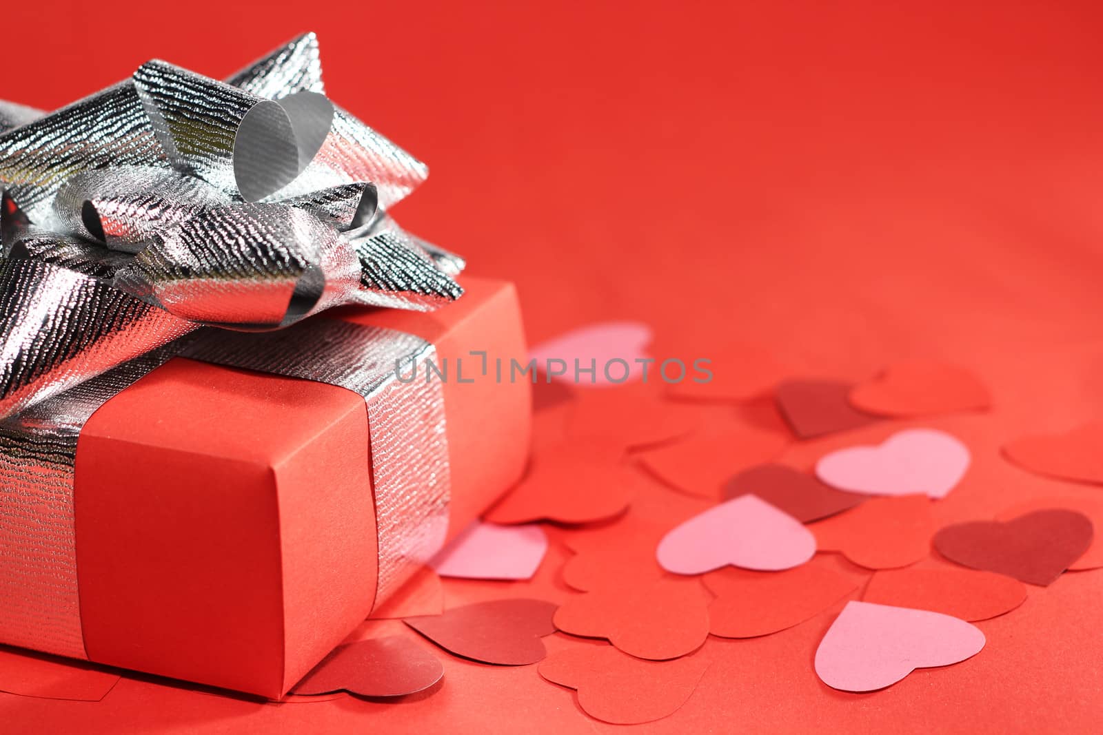 Valentines Day gift in box and small hearts on red background