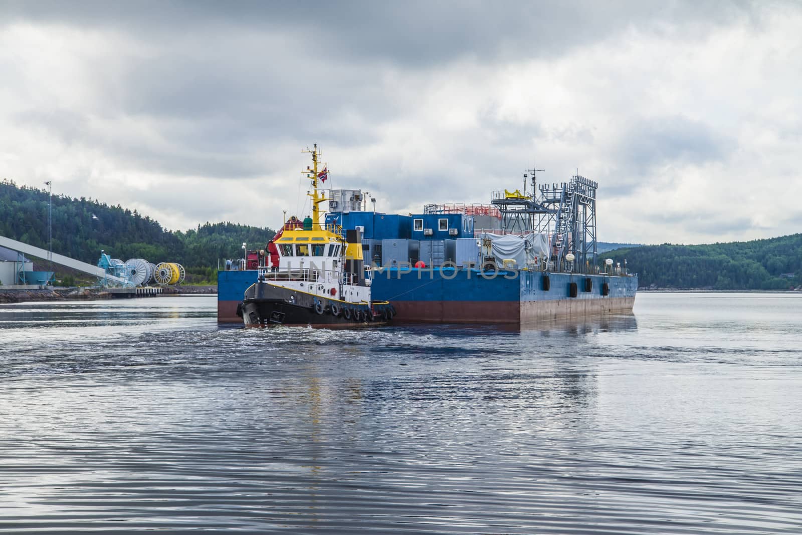 Eide Barge is towed from the pier at Halden harbor to the quay at Nexans Norway.