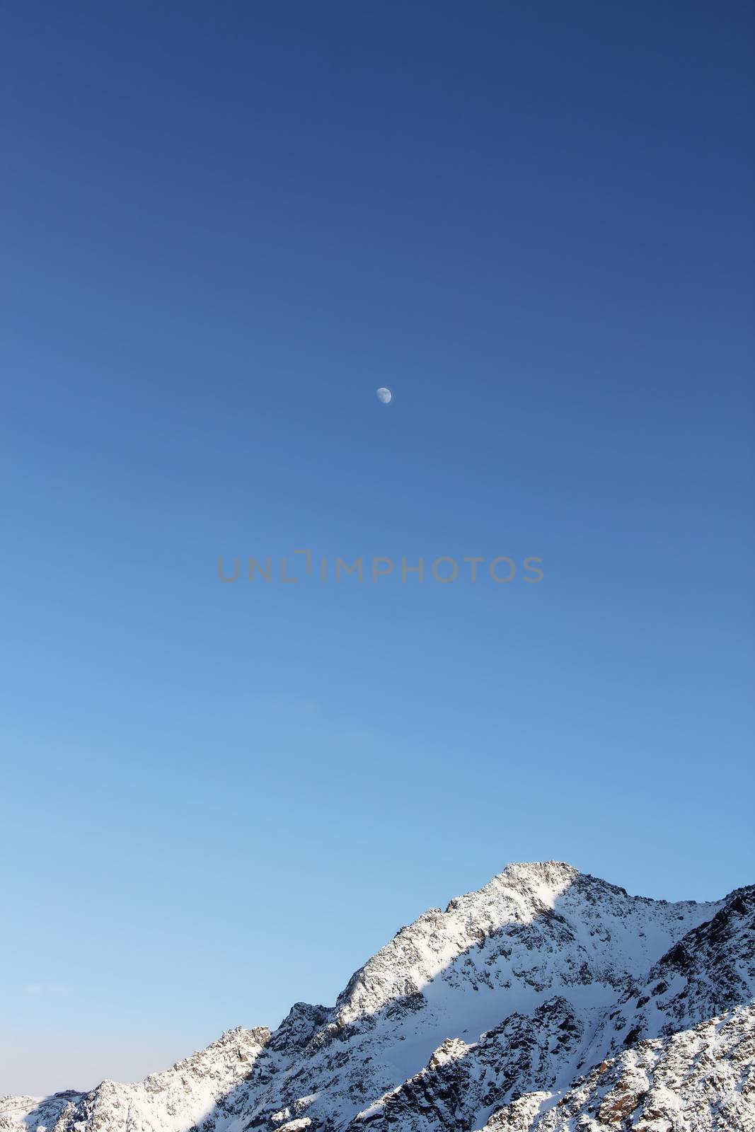 Winter alpine mountains covered with snow and moon