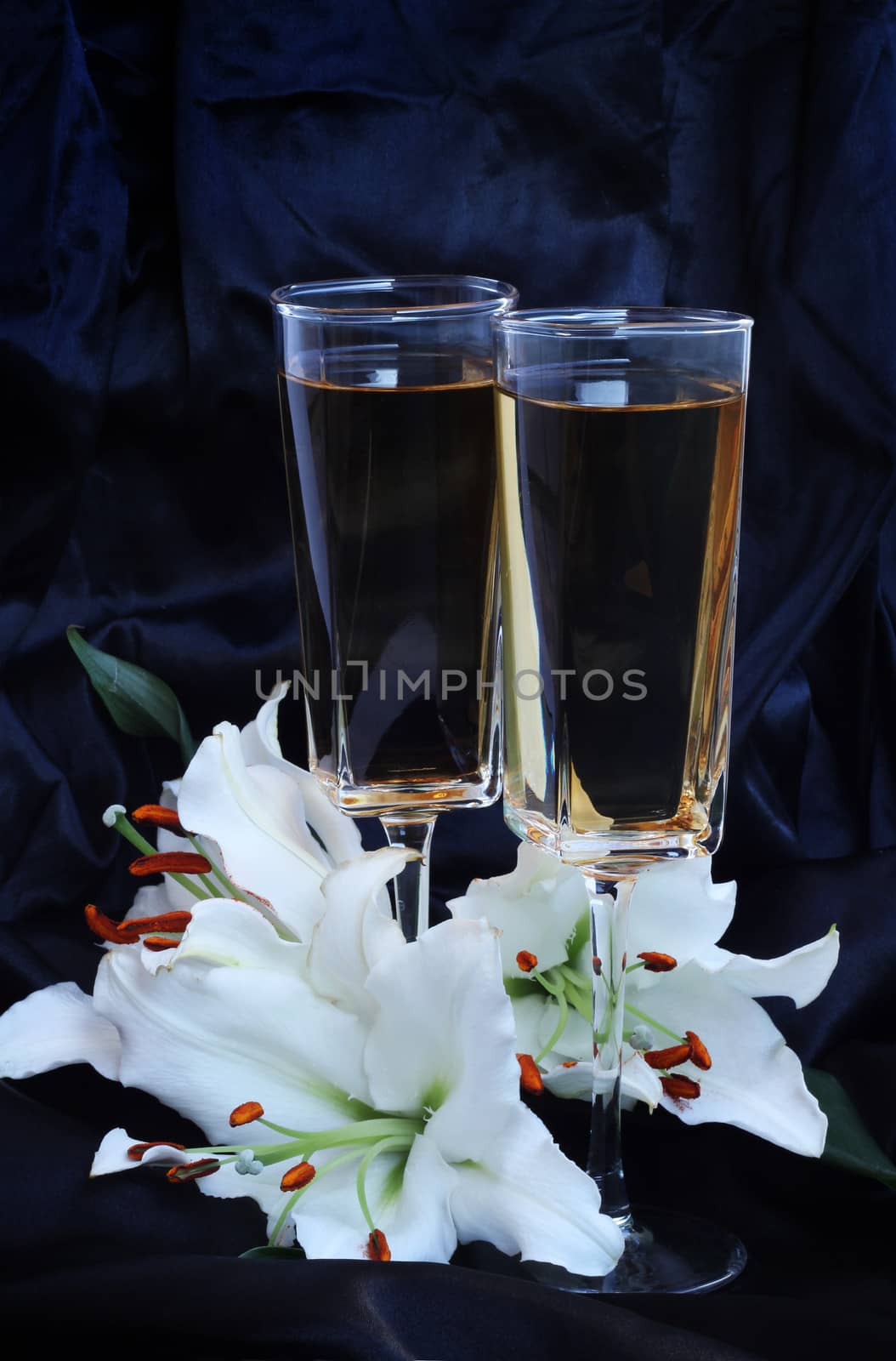 Glasses with wine and lily flower on black silk by destillat