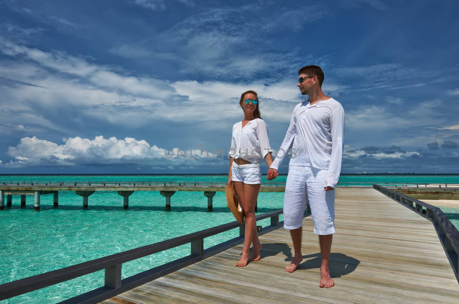 Couple on a tropical beach jetty at Maldives