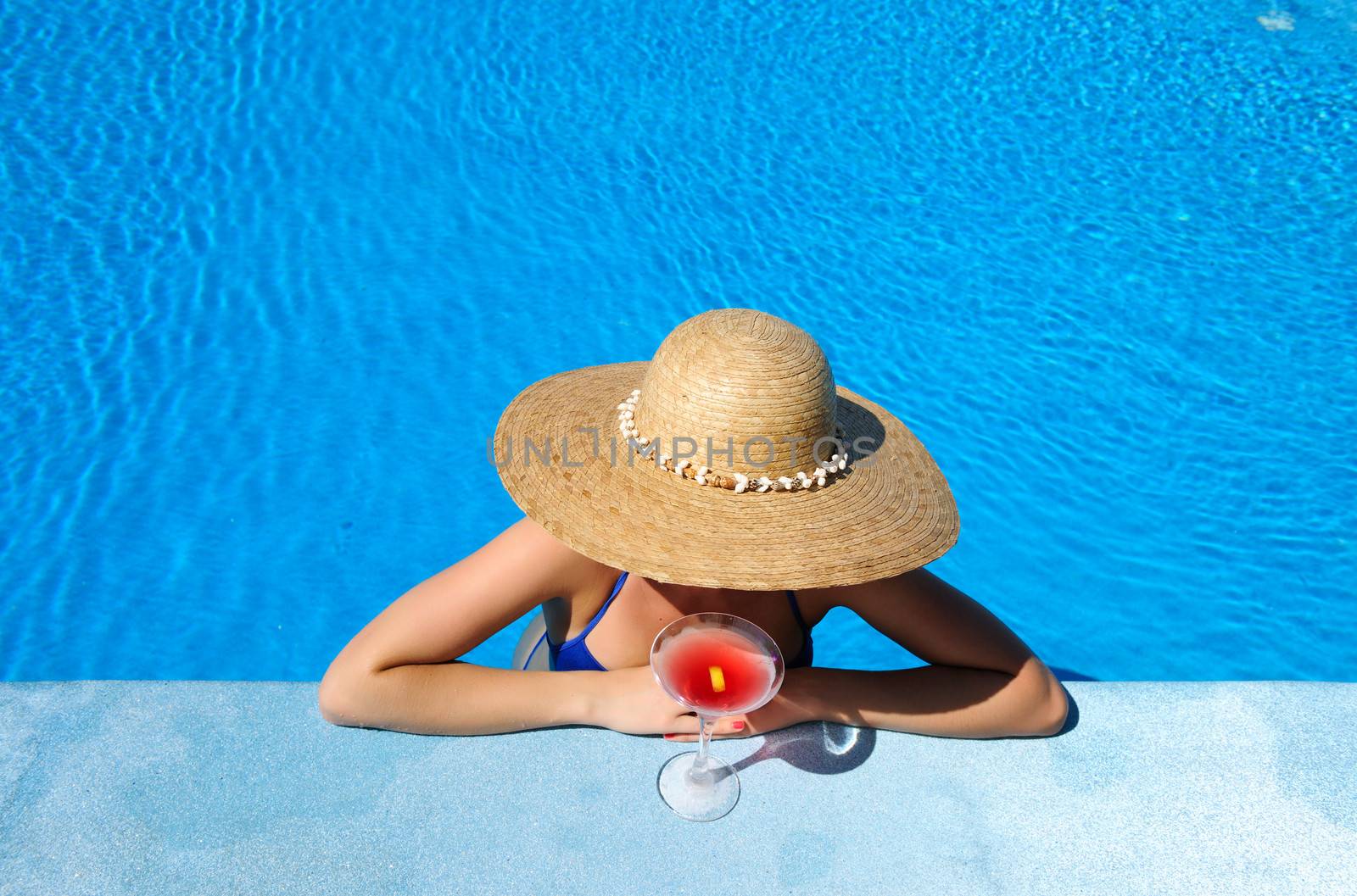 Woman at poolside with cosmopolitan cocktail by haveseen