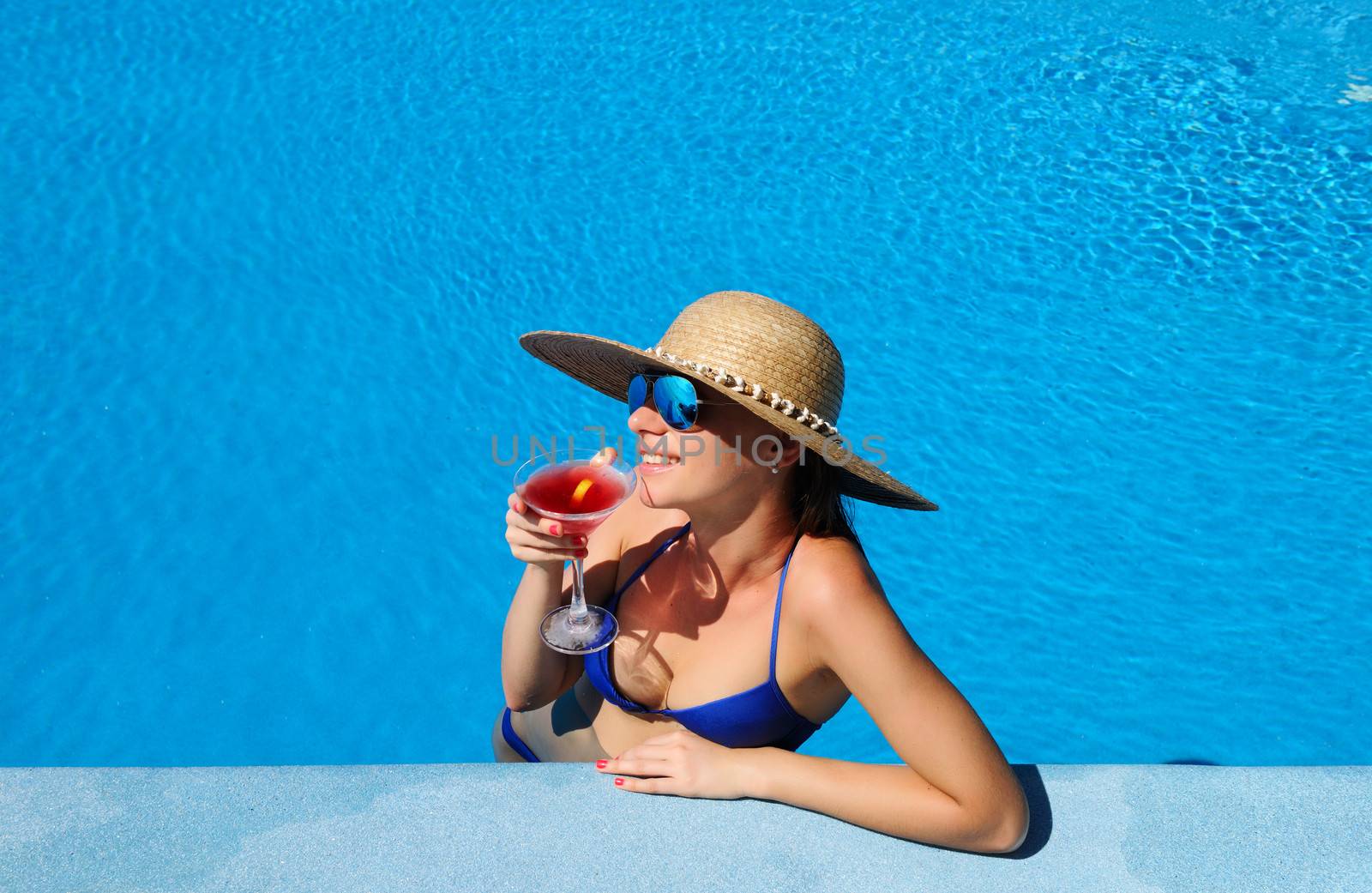 Woman at poolside with cosmopolitan cocktail by haveseen