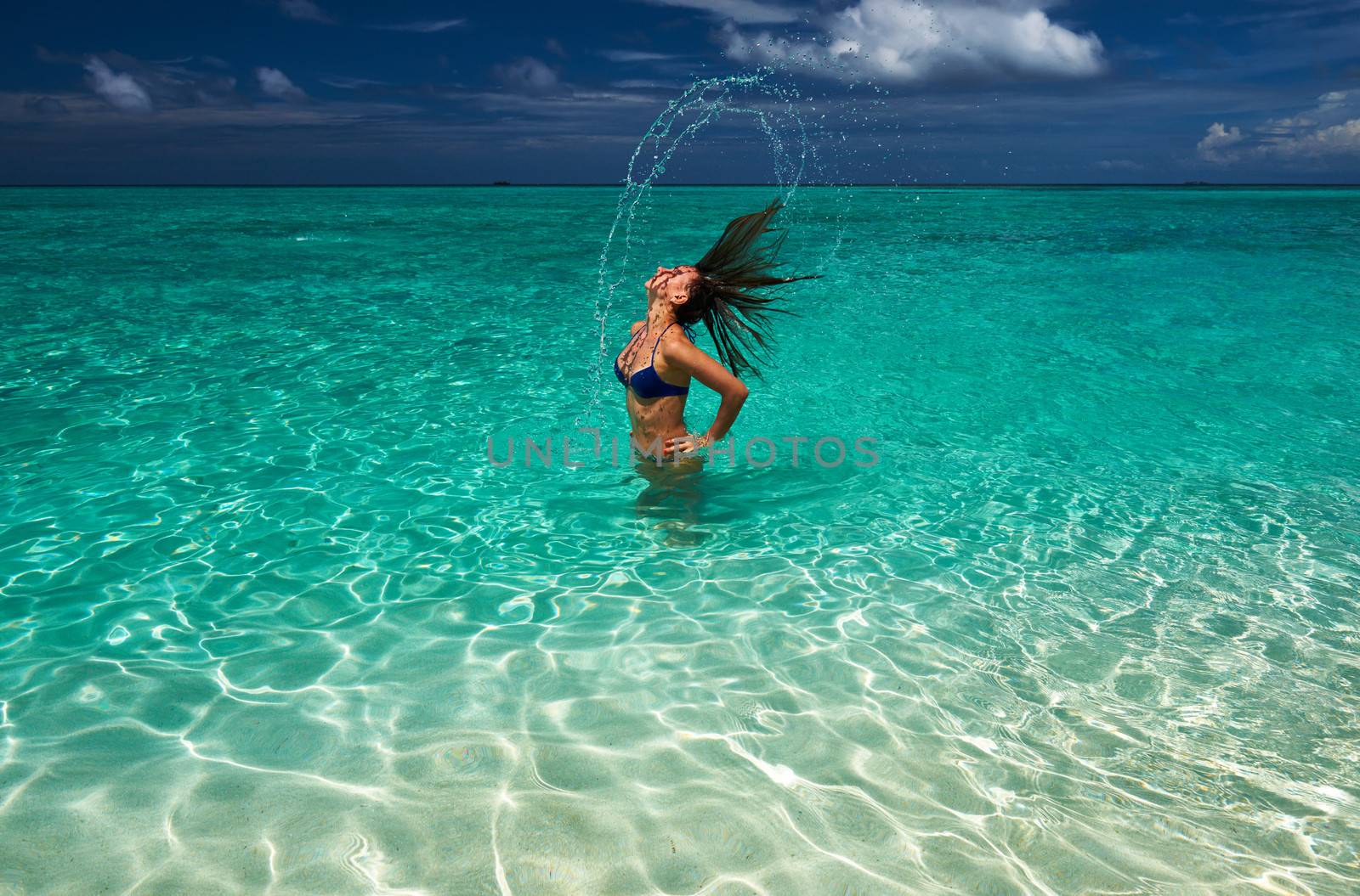 Woman splashing water with hair in the ocean by haveseen